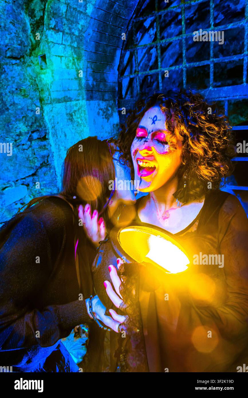 Halloween-Hexen zaubern einen Zauber mit einem glühenden Kessel in einem dunklen Verlies Stockfoto
