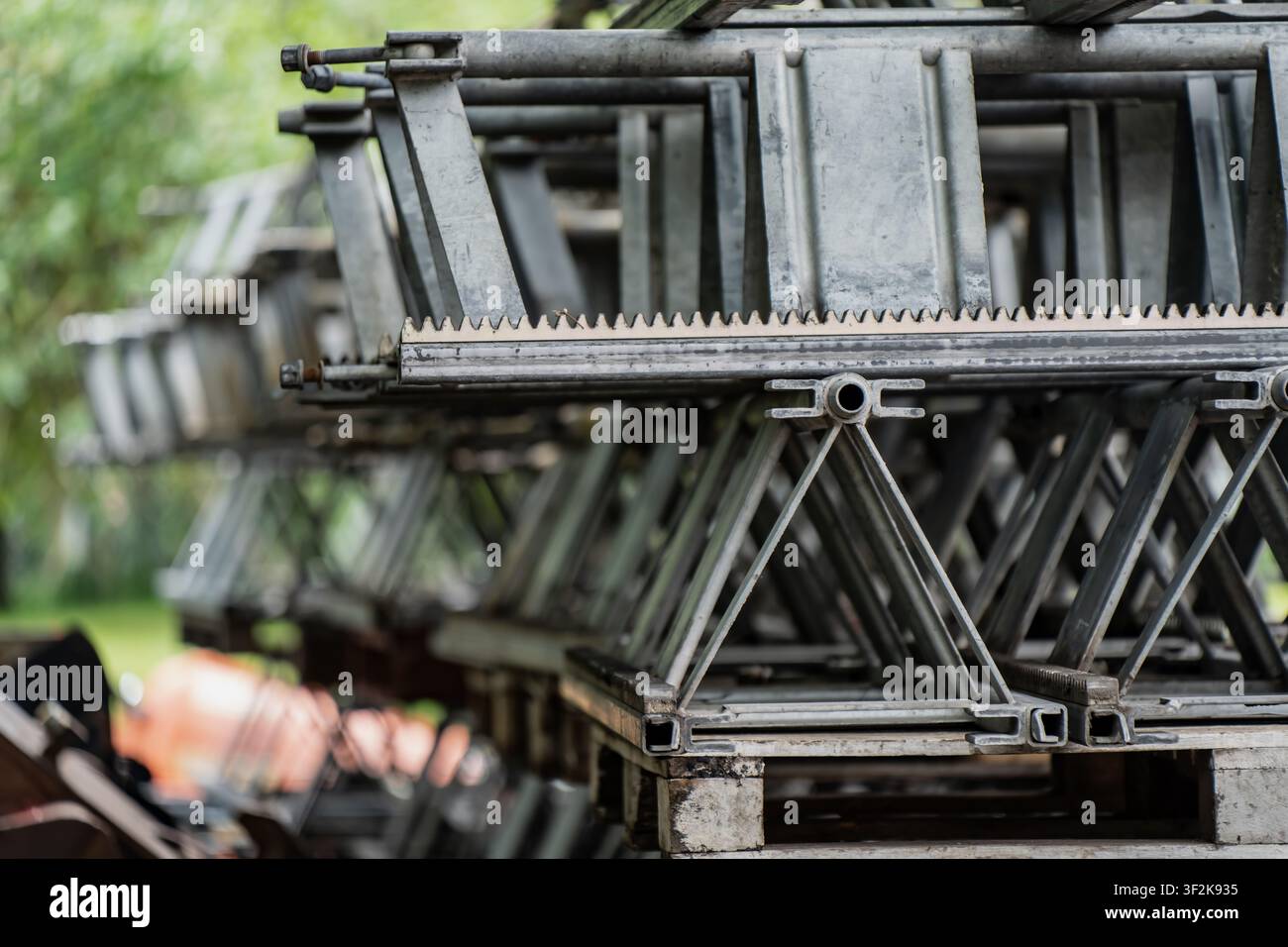 Industrielle Stahlrahmenkomponenten mit gezackten Schienenkanten, organisiert für Materialhandhabung, symbolisieren Bautechniklieferungen Stockfoto