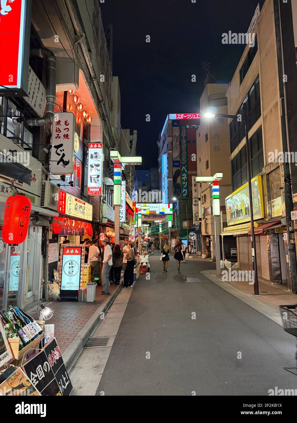 5. Oktober 2025, Bunkyo, Tokio, Japan – Lebendige nächtliche Gasse, gesäumt von leuchtenden Izakaya-Restaurants, roten Papierlaternen und japanischen Kanji-Schildern, Fußgänger gehen. - Smartphone-aufgenommenes Stockfoto