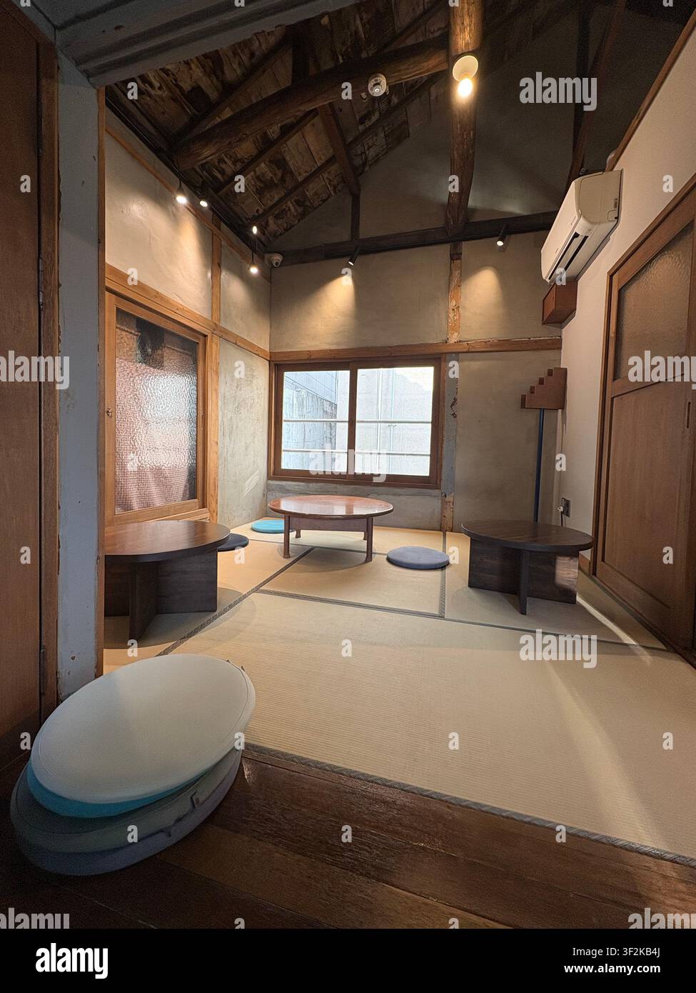 Ansicht von oben eines renovierten traditionellen koreanischen Hanok-Hauses mit freiliegenden Holzbalken, Betonwänden und modernen Möbeln, Seoul, Südkorea. - Smartphone-aufgenommenes Stockfoto