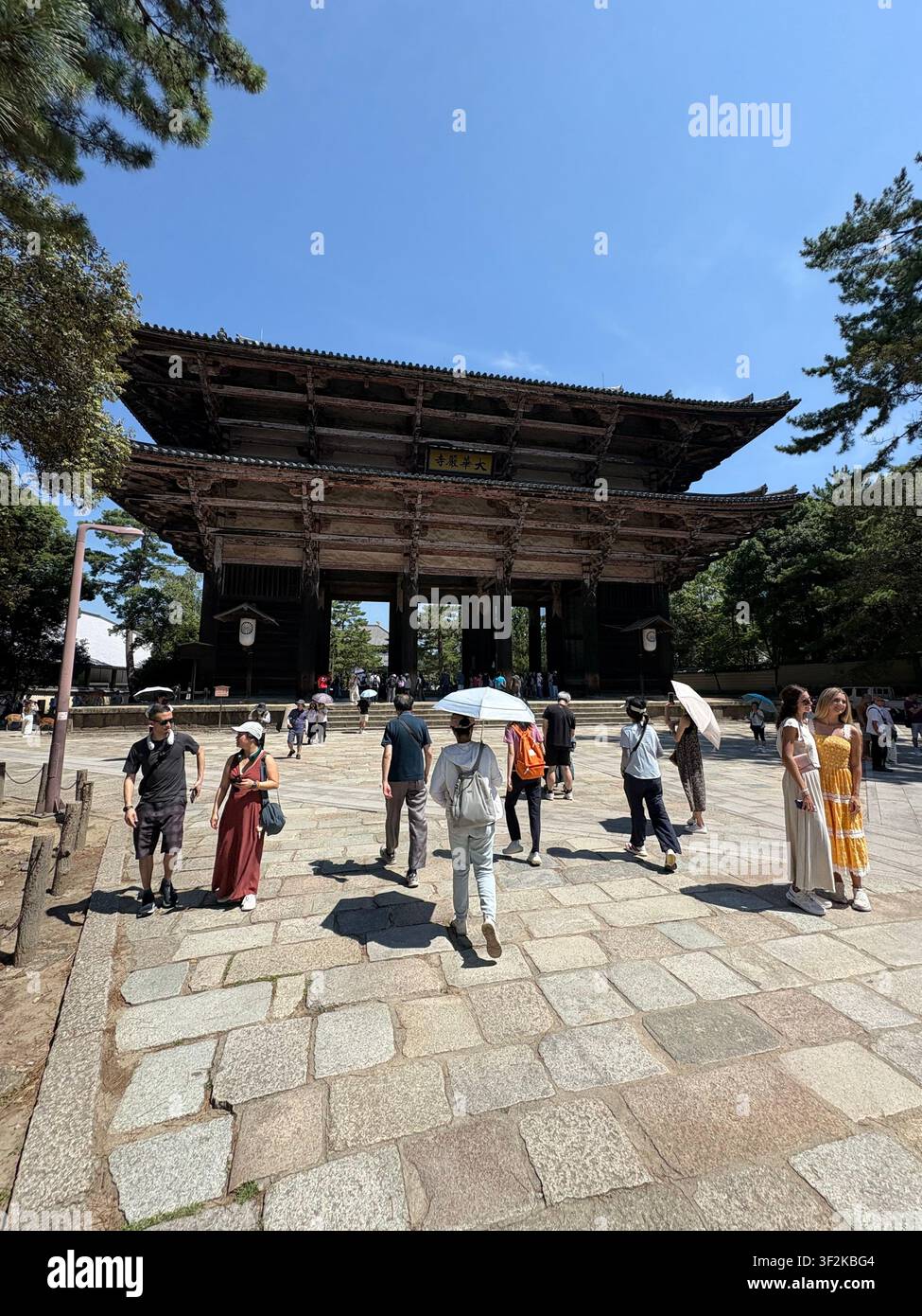 29. Juli 2025, Nara, Japan – Besucher gehen an dem historischen Nandaimon Großen Südtor des Tempelkomplexes Todai-ji unter einem klaren Sommerhimmel vorbei, Nara, Japan. - Smartphone-aufgenommenes Stockfoto