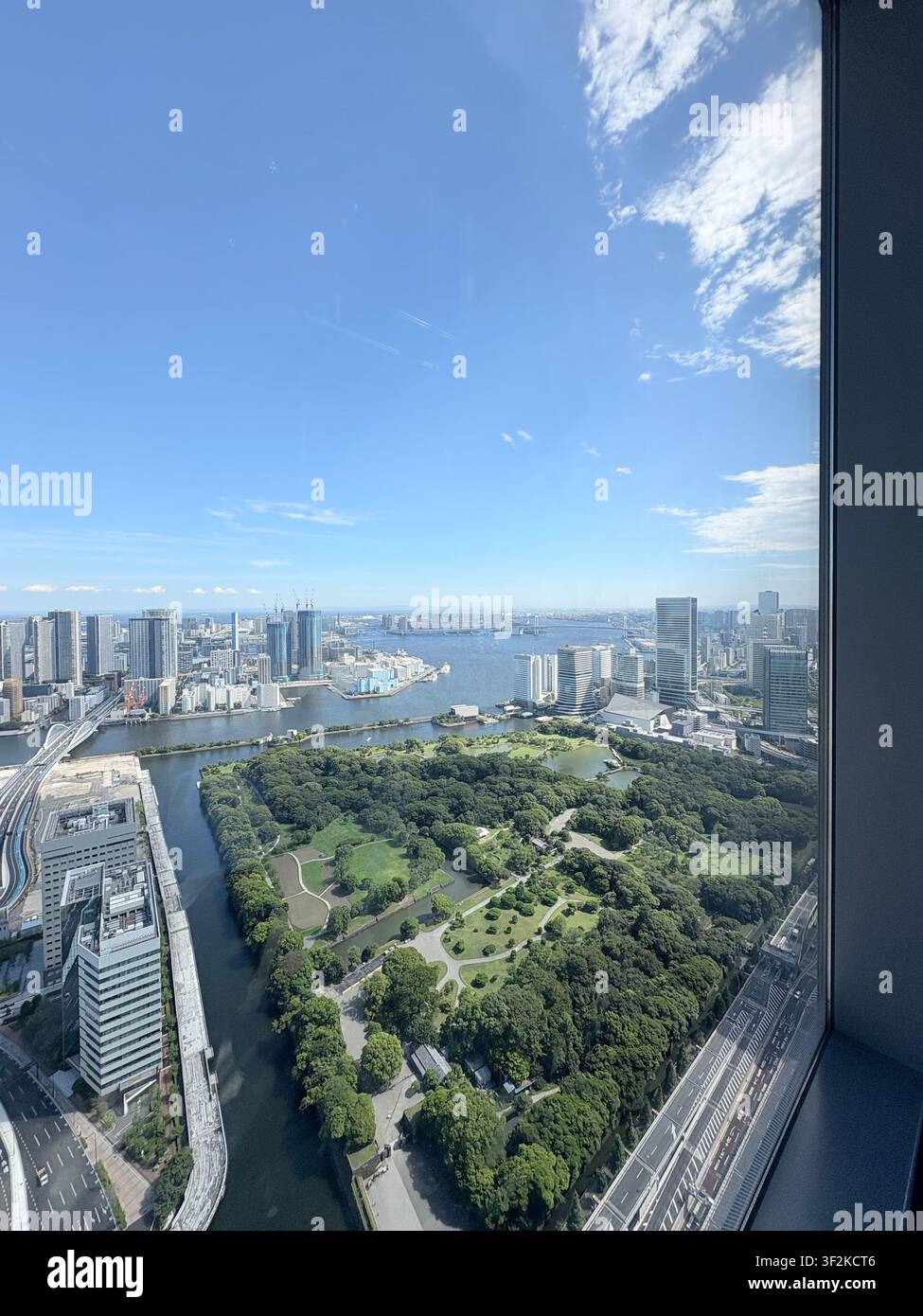 15. August 2025, Minato, Tokio, Japan – Luftaufnahme vom Beobachtungsplateau mit Blick auf die Skyline von Tokio, die Grünflächen der Hamarikyu-Gärten und den Sumida-Flusskanal, Japan. - Smartphone-aufgenommenes Stockfoto