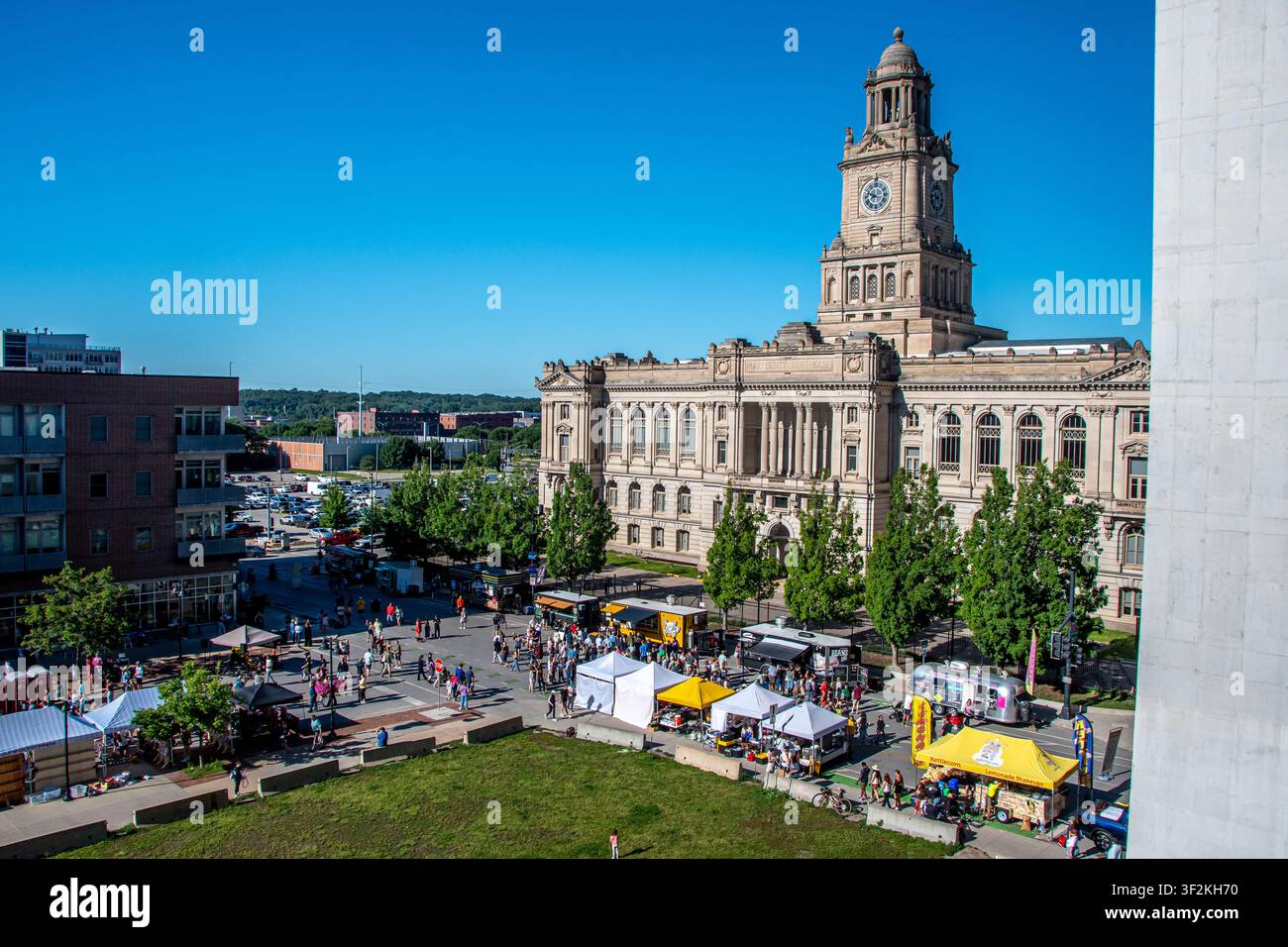 Historisches Gerichtsgebäude von Polk County in der Innenstadt von Des Moines, Iowa, während eines Bauernmarkts am Samstag, mit Zelten, Händlern und Menschenmengen unter einem blauen Himmel. Stockfoto