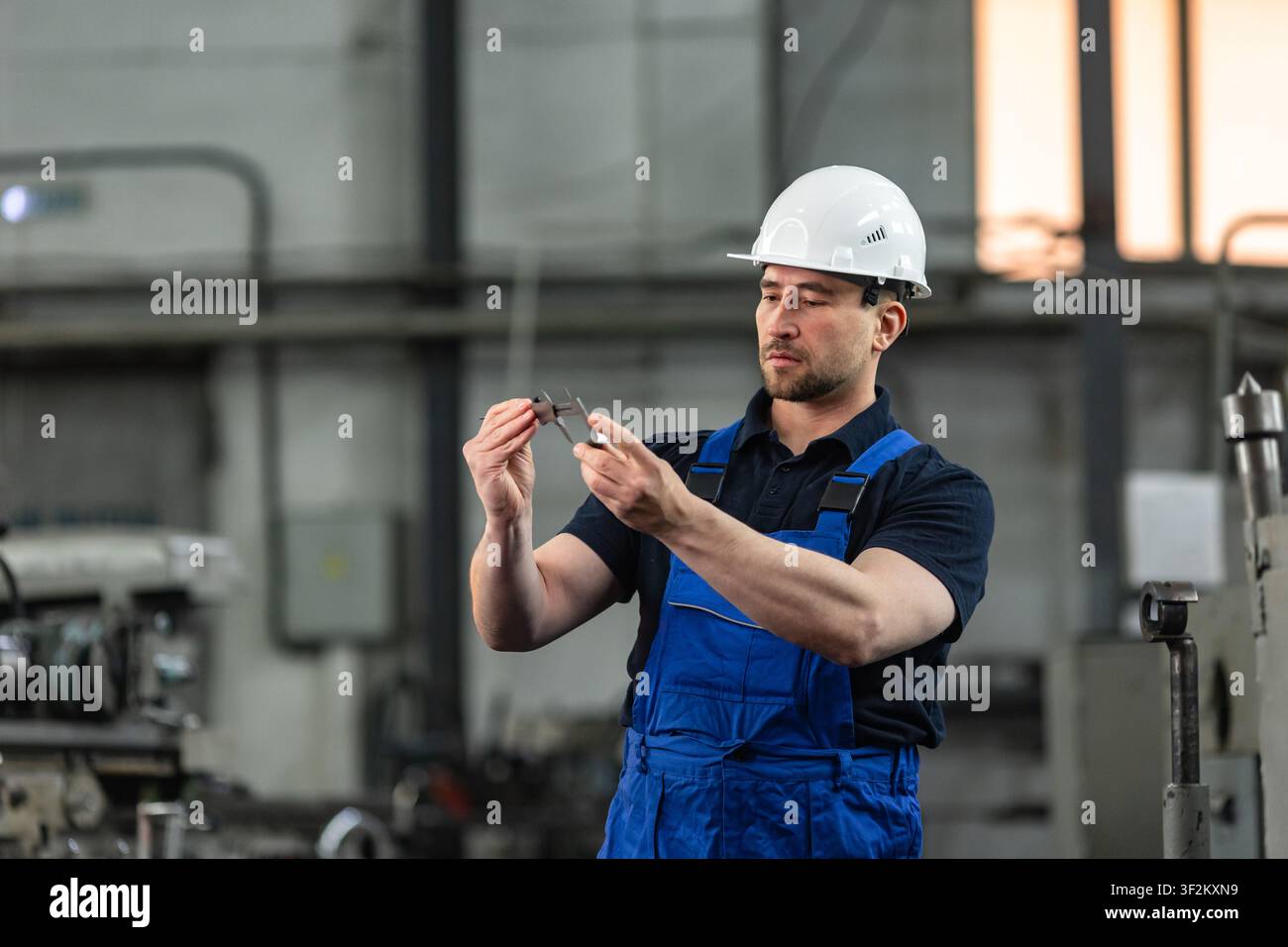 Industriearbeiter misst Metallteil mit Messschieber in einer Fertigungsfabrik Stockfoto