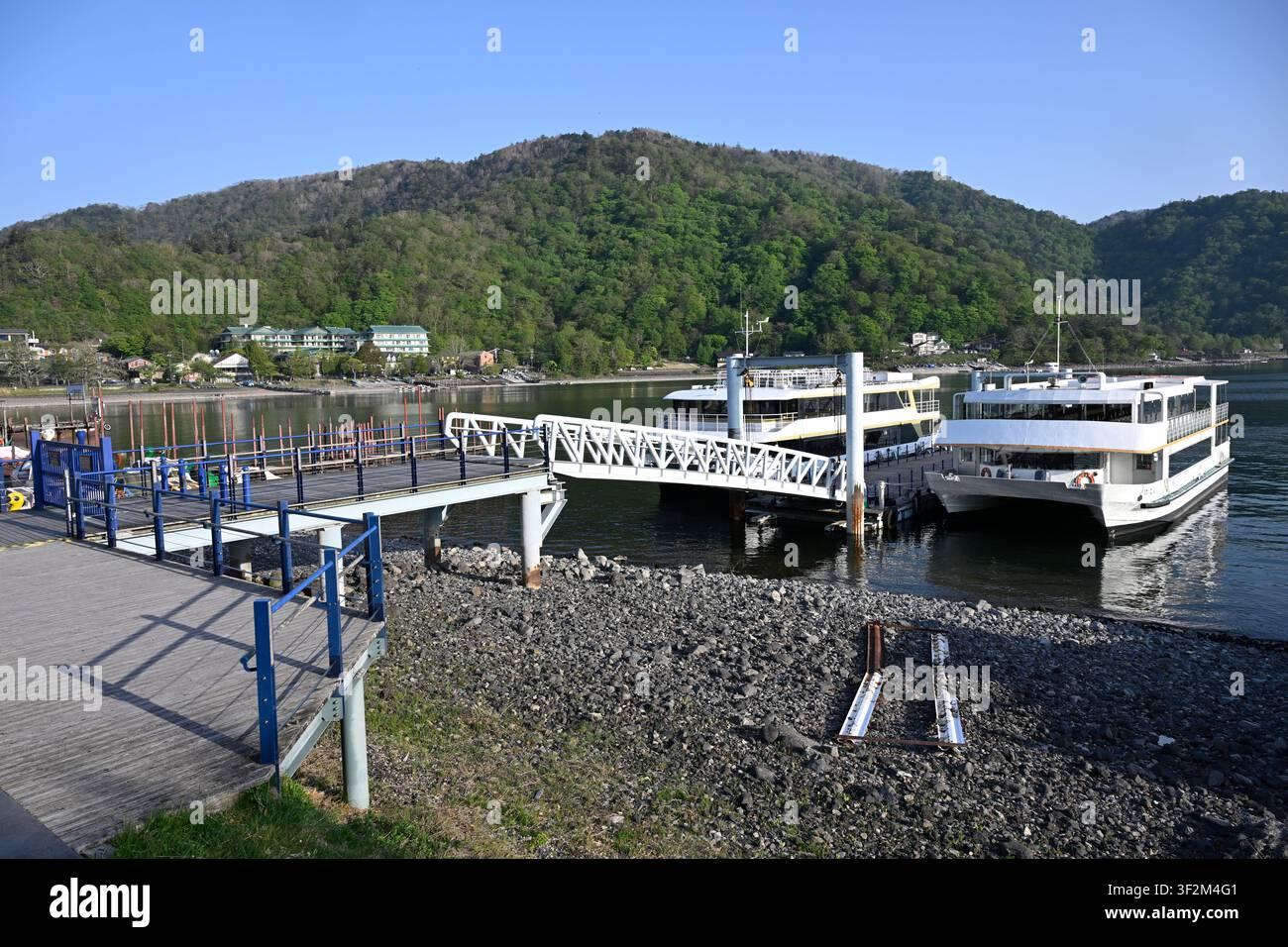 Ausflugsboote, die am Pier an den friedlichen Ufern des Chuzenji-Sees im Nikko-Nationalpark, Präfektur Tochigi, Japan, festgemacht sind. Umgeben von Wald Stockfoto