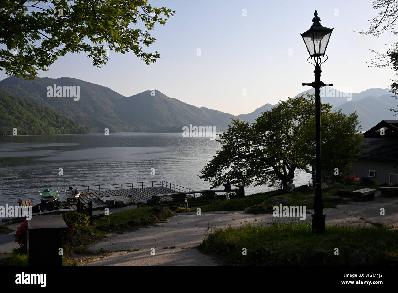 Ein ruhiger Blick auf den Chuzenji-See bei Sonnenuntergang im Nikko-Nationalpark, Präfektur Tochigi, Japan. Umgeben von bewaldeten Bergen, das Seeufer, klein p Stockfoto