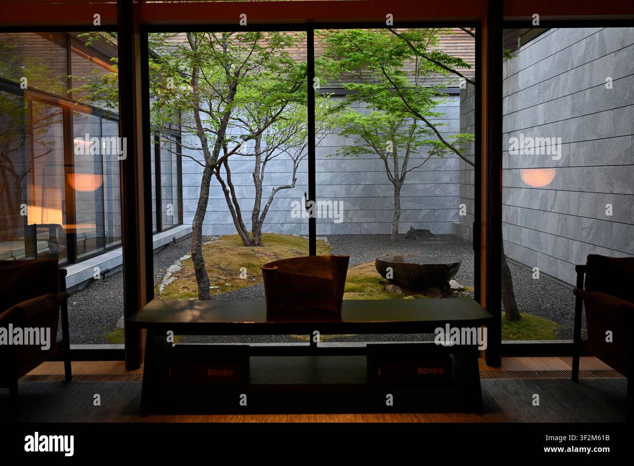 Japanischer Innenhofgarten, gesehen von einer modernen Luxushotel-Lounge in Nikko, Präfektur Tochigi, Japan. Ganzkörperfenster rahmen ein minimalistisches Stockfoto