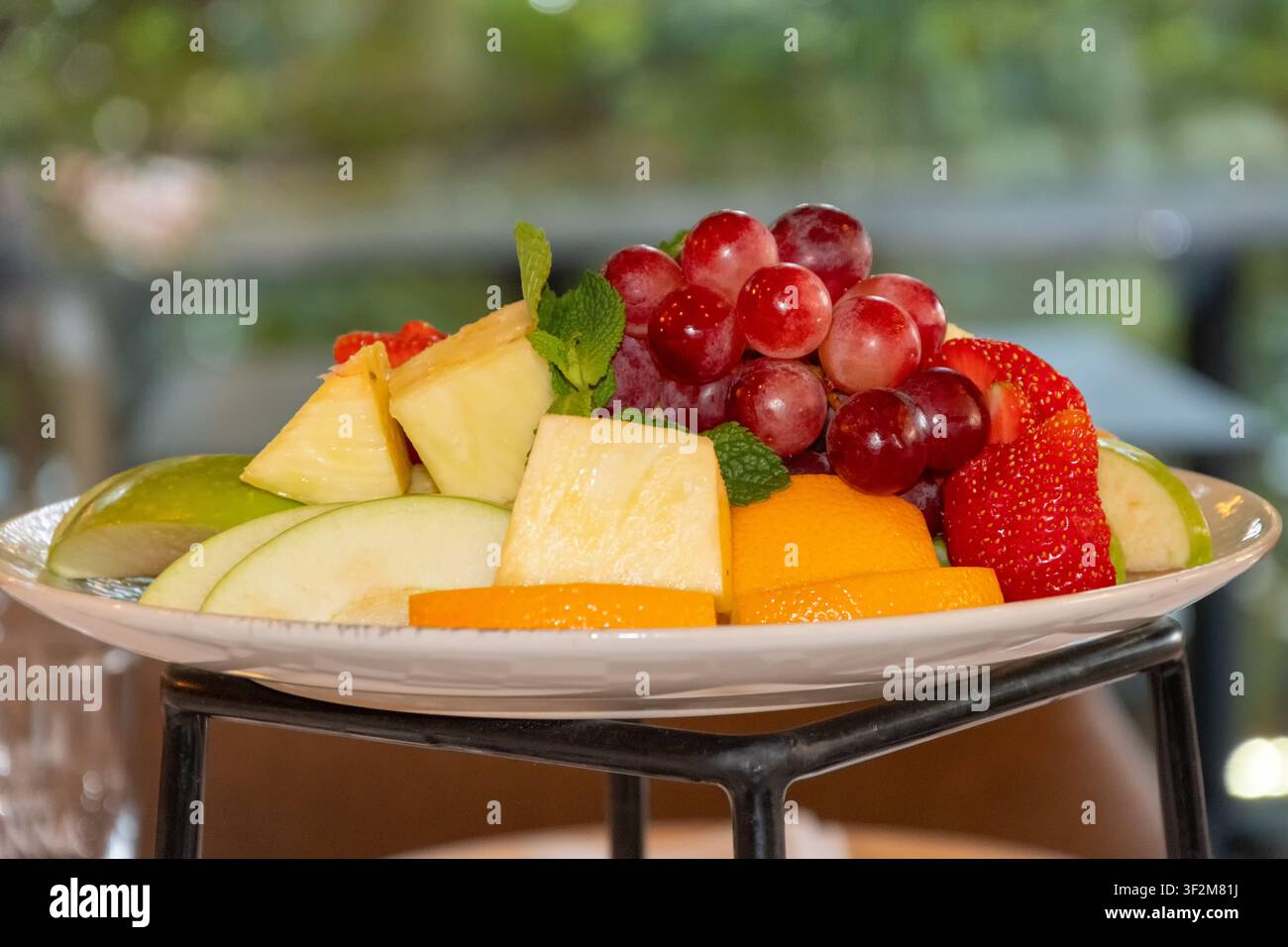 Frisches Obstsalat mit Trauben, Ananas, Äpfeln, Erdbeeren, Orangen und Minze, serviert für ein gesundes Restaurant-Frühstücksbuffet. Stockfoto