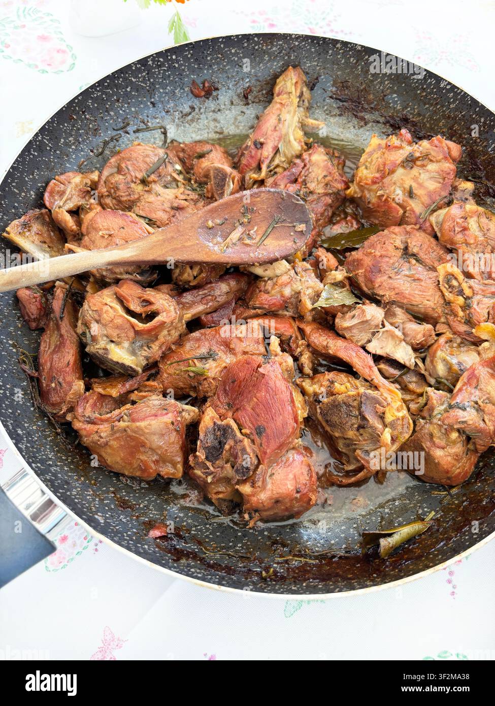 Geschmorte Lammstücke, in einer Pfanne mit Rosmarin und Lorbeerblättern gekocht. Traditionelles Gericht der authentischen italienischen Küche. Blick von oben. Stockfoto