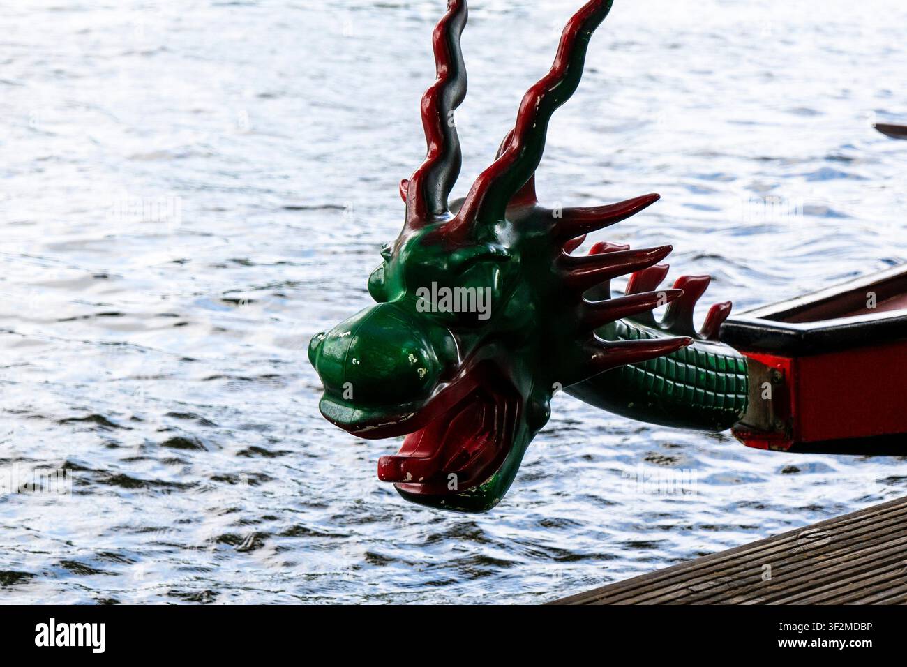 Detaillierte Nahaufnahme einer geschnitzten grünen und roten Drachenkopf-Figur am Bug eines traditionellen Drachenboots Stockfoto