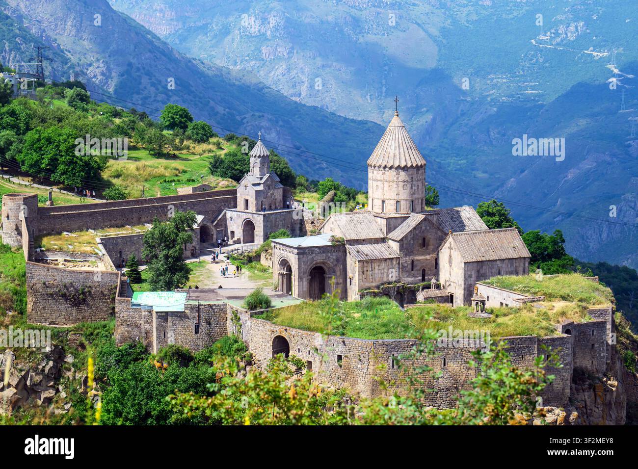 Altes Tatev-Kloster auf einem Bergrücken. Steinbauten mit Kuppeltürmen. Umgebende Hügel bedeckt mit grüner Vegetation Stockfoto