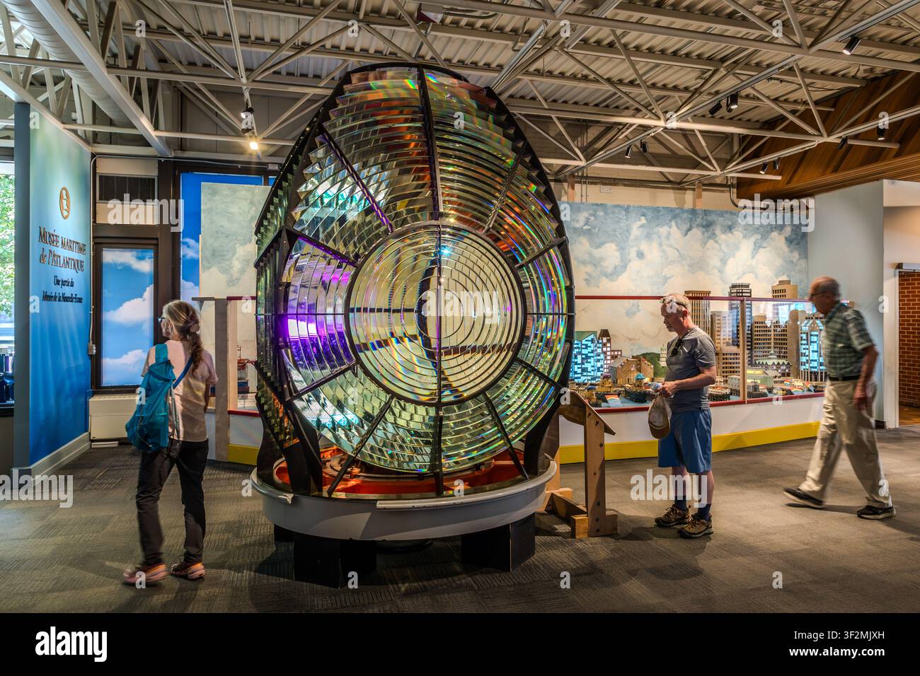 Eine historische Fresnel-Leuchtturmlinse vor einem Modell der Skyline von Halifax, ausgestellt im Maritime Museum of the Atlantic in Halifax, Nova Scotia, Kanada. Halifax, Nova Scotia, Kanada Stockfoto
