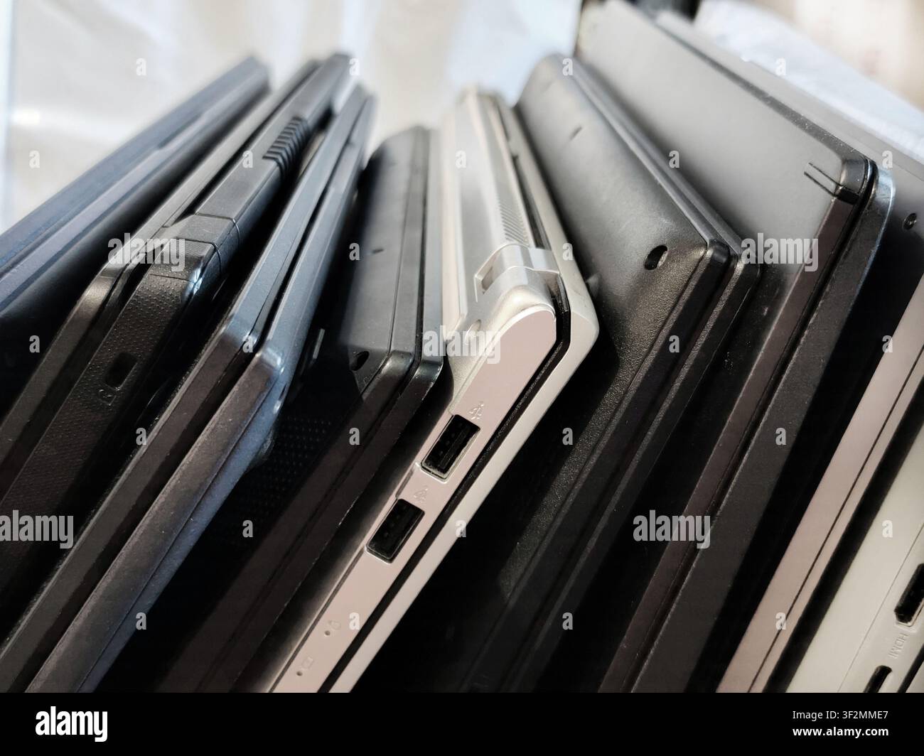 Mehrere moderne Laptop-Computer nebeneinander gestapelt, die USB-Anschlüsse und Aluminiumgehäuse zeigen. Technologievergleich, Computerhardware, Büroausstattung Stockfoto