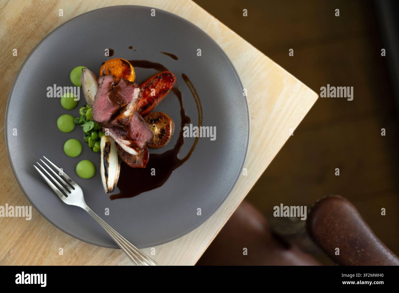 Gourmet-Gericht mit perfekt gegartem Fleisch und farbenfrohen Gemüsen auf einem stilvollen Teller Stockfoto