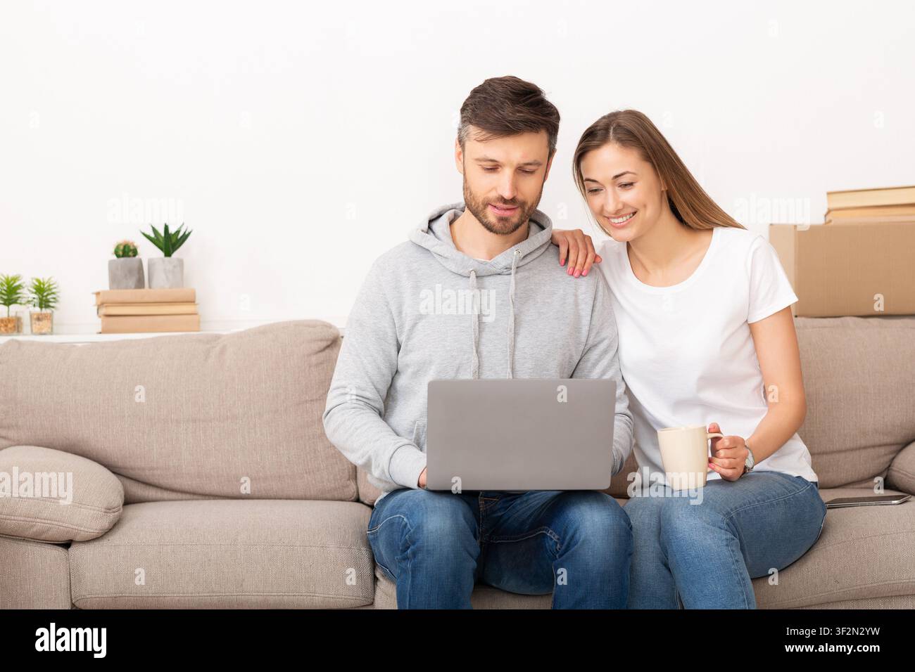 Junge Paare, die mit einem Laptop ein intelligentes Zuhause einrichten Stockfoto