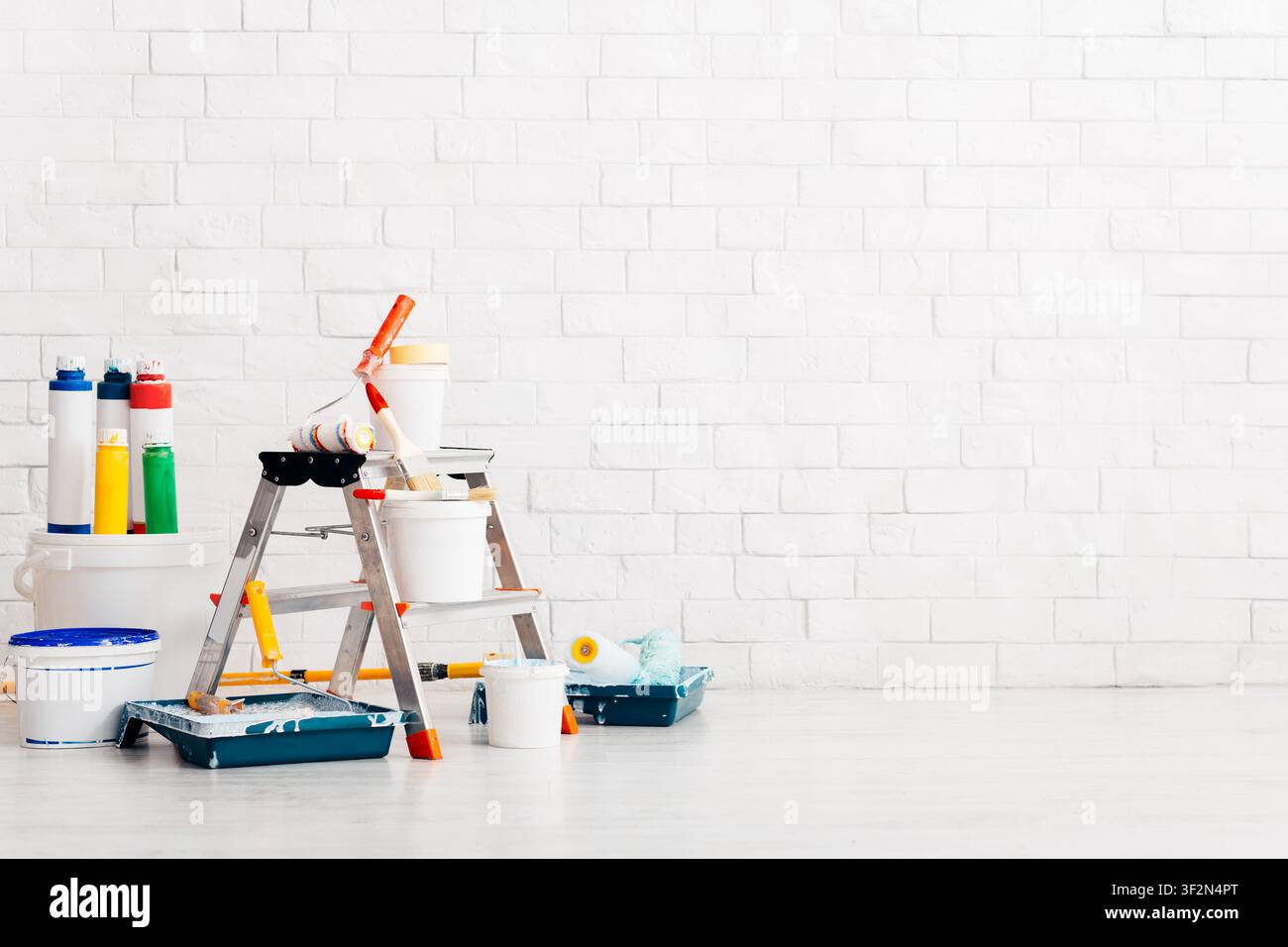 Wand bei Renovierung mit Leiter und Farbkeimer im leeren Raum Stockfoto