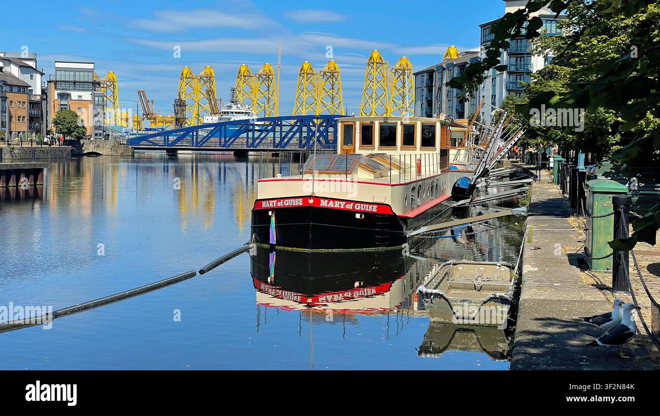 Maria von Guise am The Shore, mit gelben Gitterturmstrukturen, die für ein Offshore-Windprojekt im Hintergrund gefertigt werden, Leith Edinburgh, Schottland - Smartphone-aufgenommenes Stockfoto