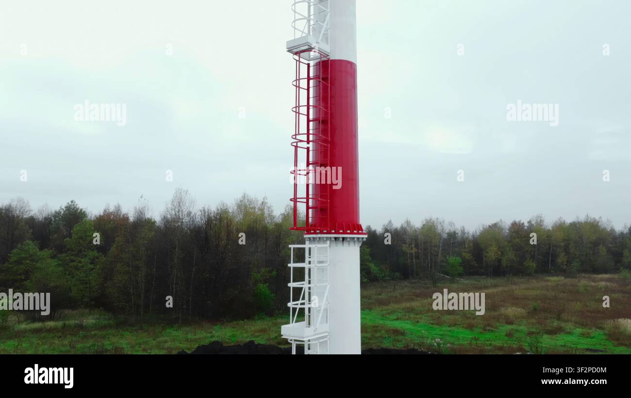 Hoher Industriekamin mit umschlossener Leiter am Waldrand Stockfoto