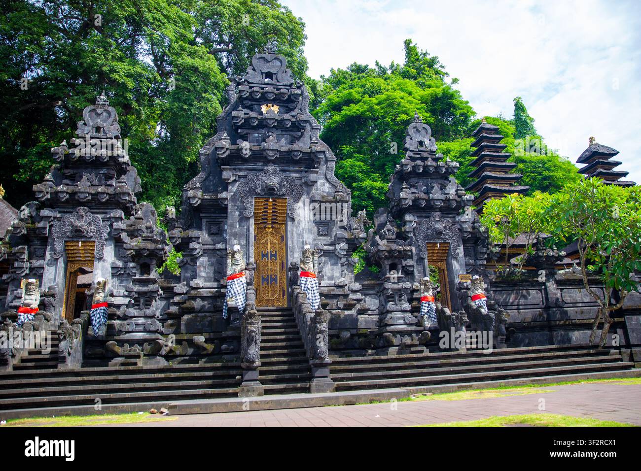 Die kunstvollen schwarzen Vulkangestein-Schreine und Wächterstatuen des historischen Pura Goa Lawah Tempelkomsplexes auf Bali. Stockfoto