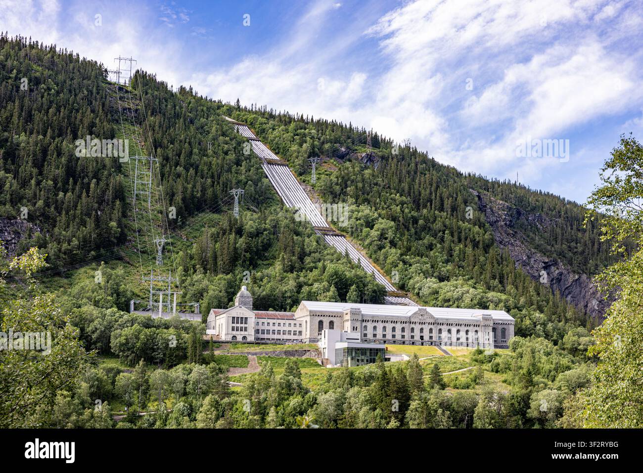 Vemork, Rjukan, Telemark, Norwegen. Kraftwerk. Großes Gebäude, eingebettet zwischen üppigen grünen Hügeln. Ein geneigter Gleisweg schneidet sich durch einen dicht bewaldeten Berghang. B Stockfoto