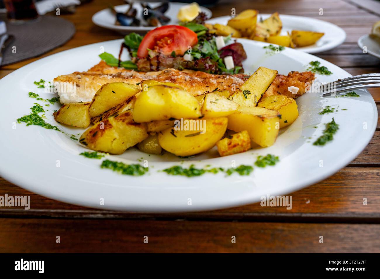 Gegrillter Zander mit Salat und Kräuter und Kartoffel auf weißem Teller auf dem Tisch, Essen. Stockfoto