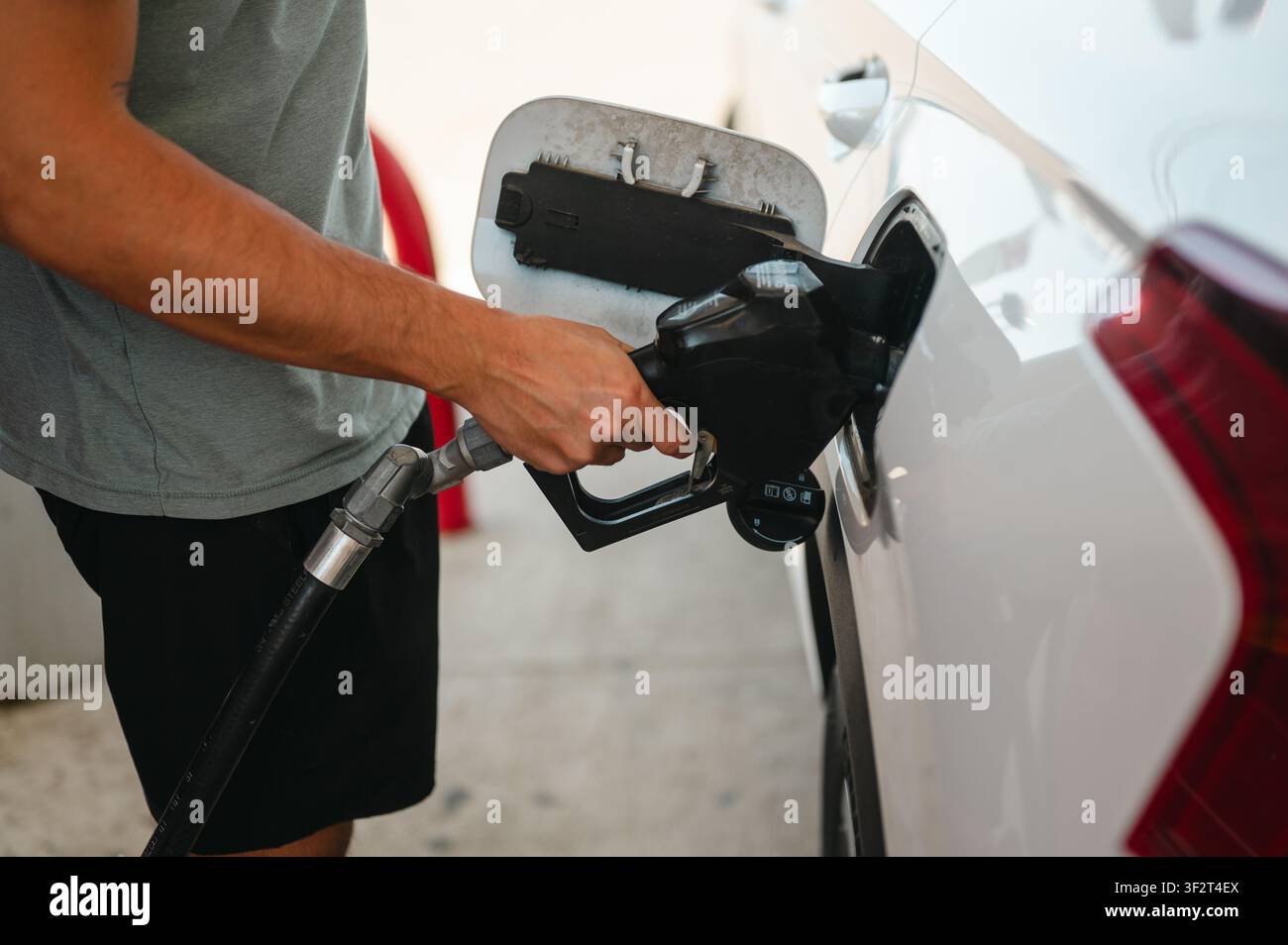Mann tankt ein weißes Auto an einer Tankstelle Stockfoto
