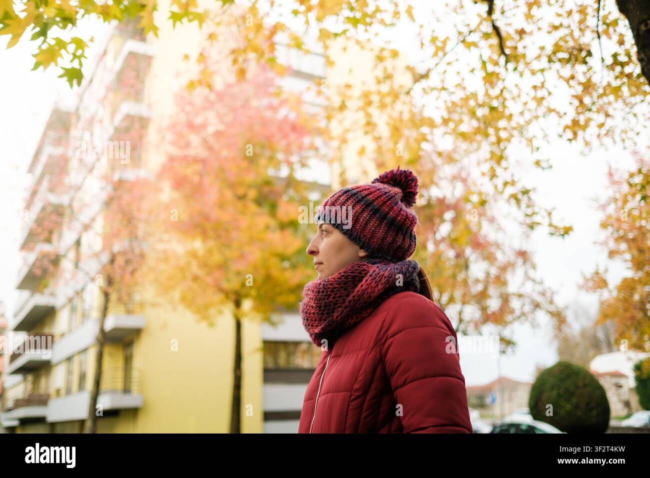 Frau mit Beanie und Schal, die im Herbst draußen spazieren geht Stockfoto