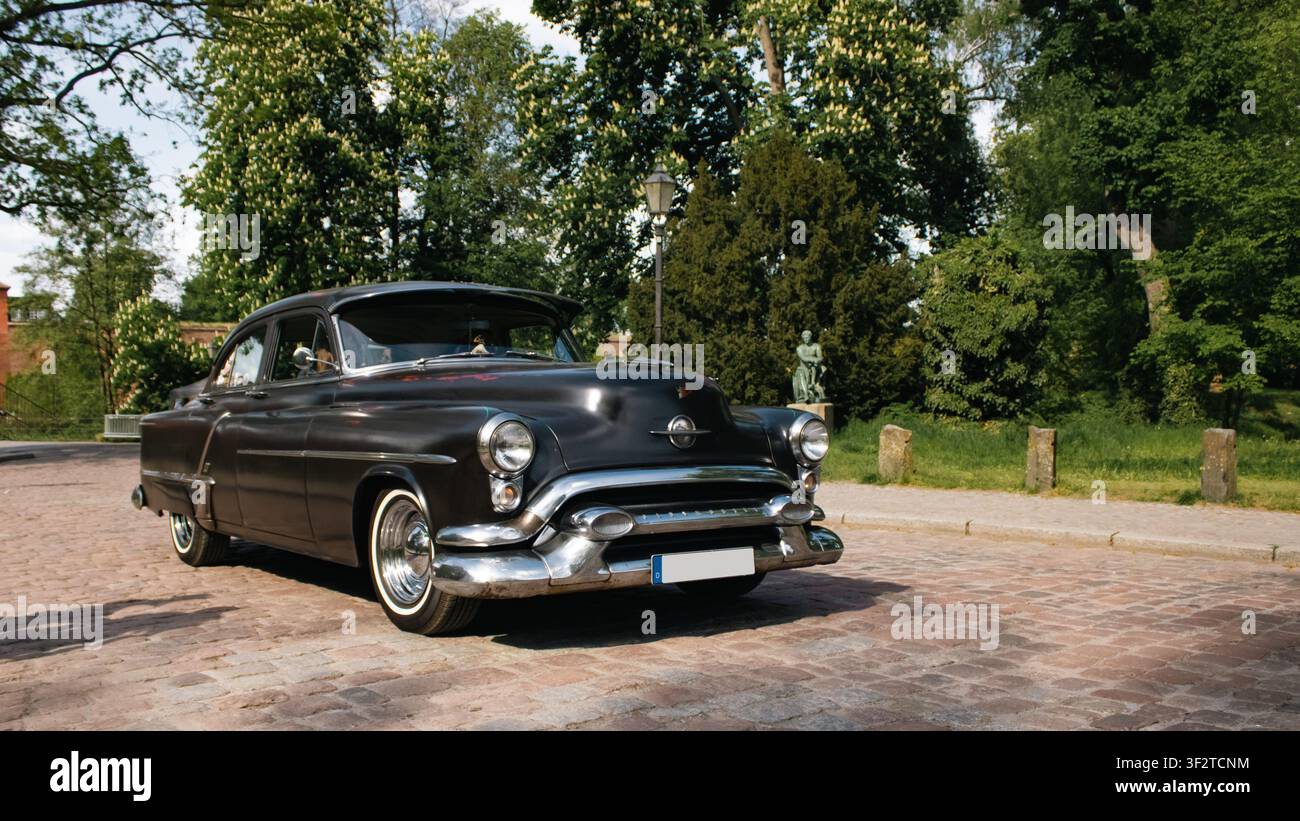 Berlin, Deutschland - 3. Mai 2026. Dunkler Vintage-Oldsmobile-Limousine mit Chrom-Kühlergrill, Weißwandreifen und abgerundeter 1950er-Styling beim Oldtimer Open Air in Zit Stockfoto