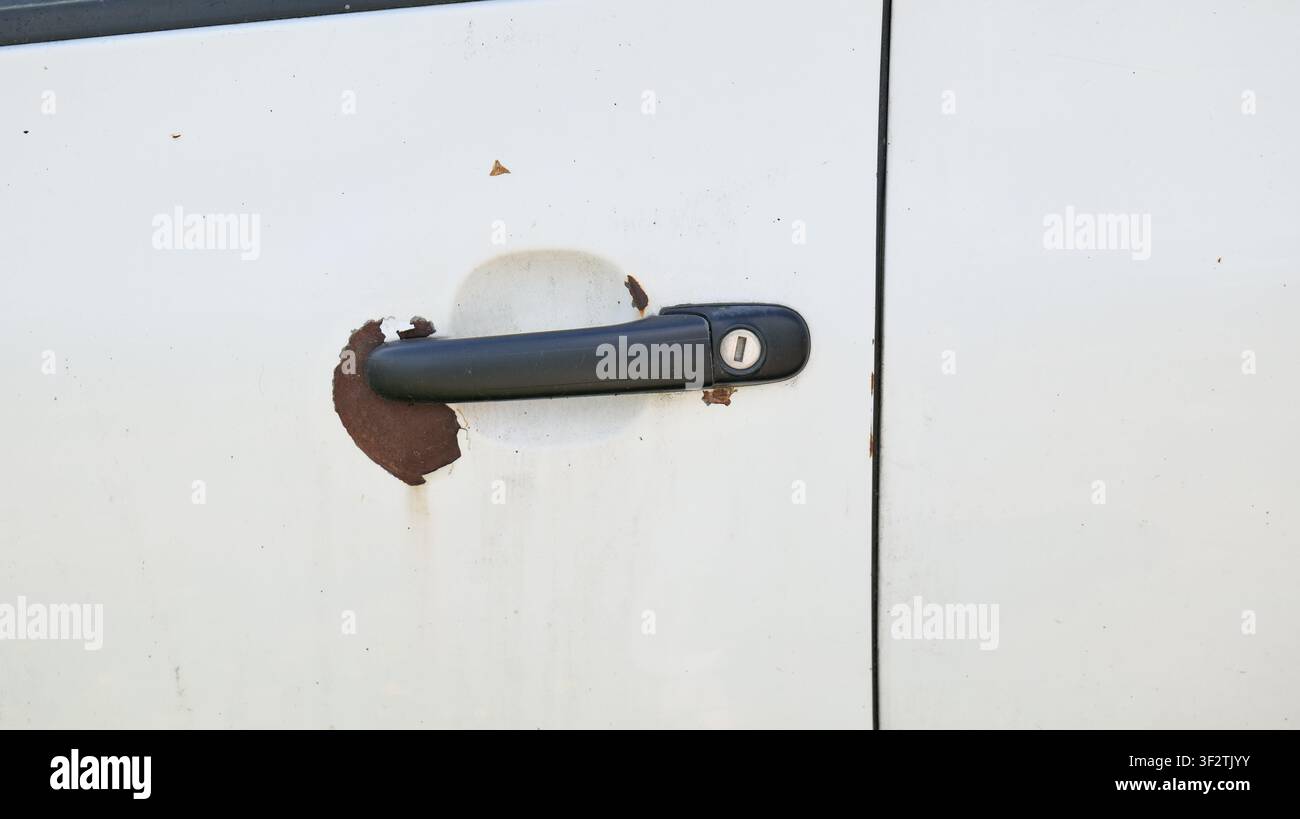 Rostige Autotürgriff an einem weißen Fahrzeug, Nahaufnahme Stockfoto