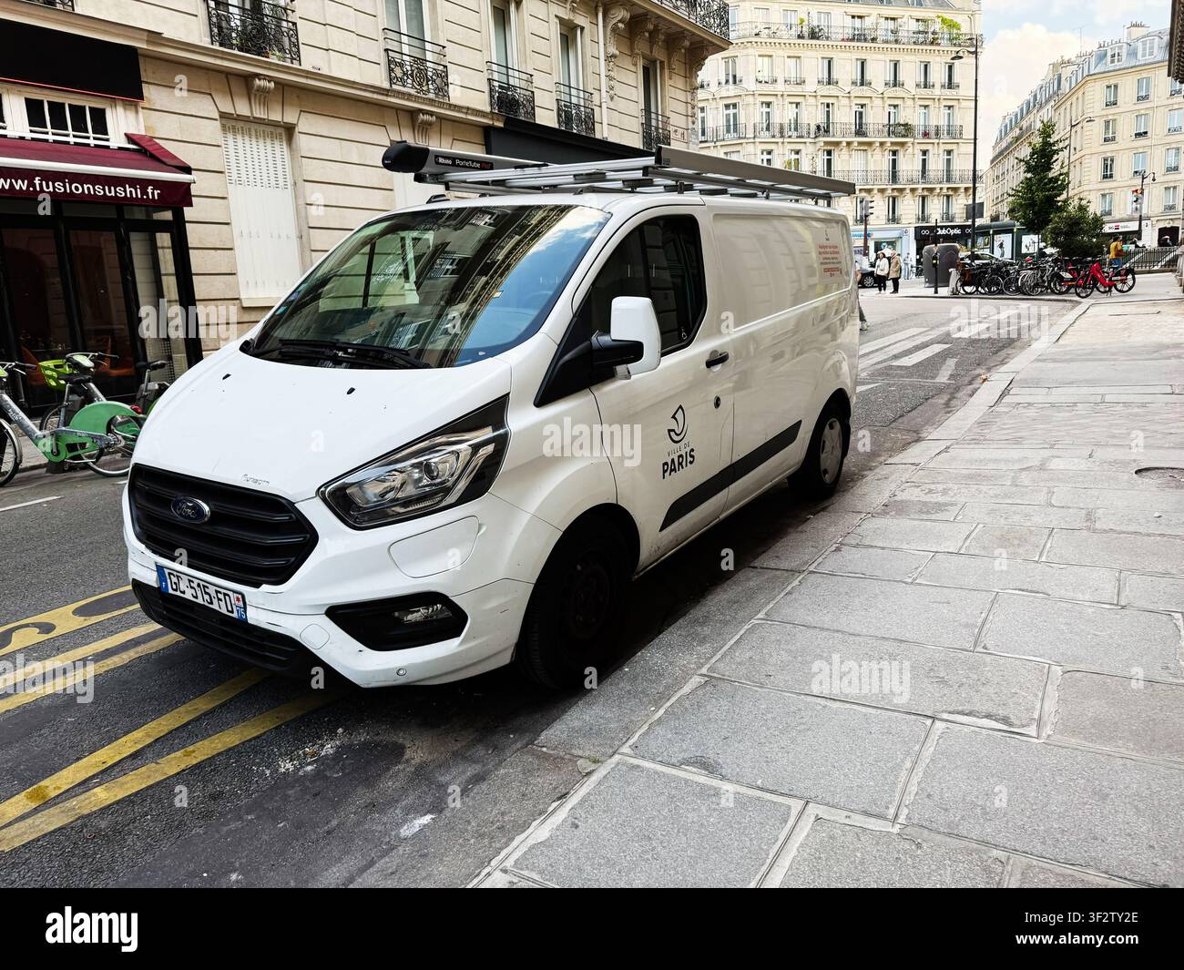 Paris, Frankreich – 14. Mai 2026: Weißer gewerblicher Transporter, der entlang einer belebten Pariser Straße mit Fahrrädern, Gebäuden und urbanen Details geparkt ist. Stockfoto