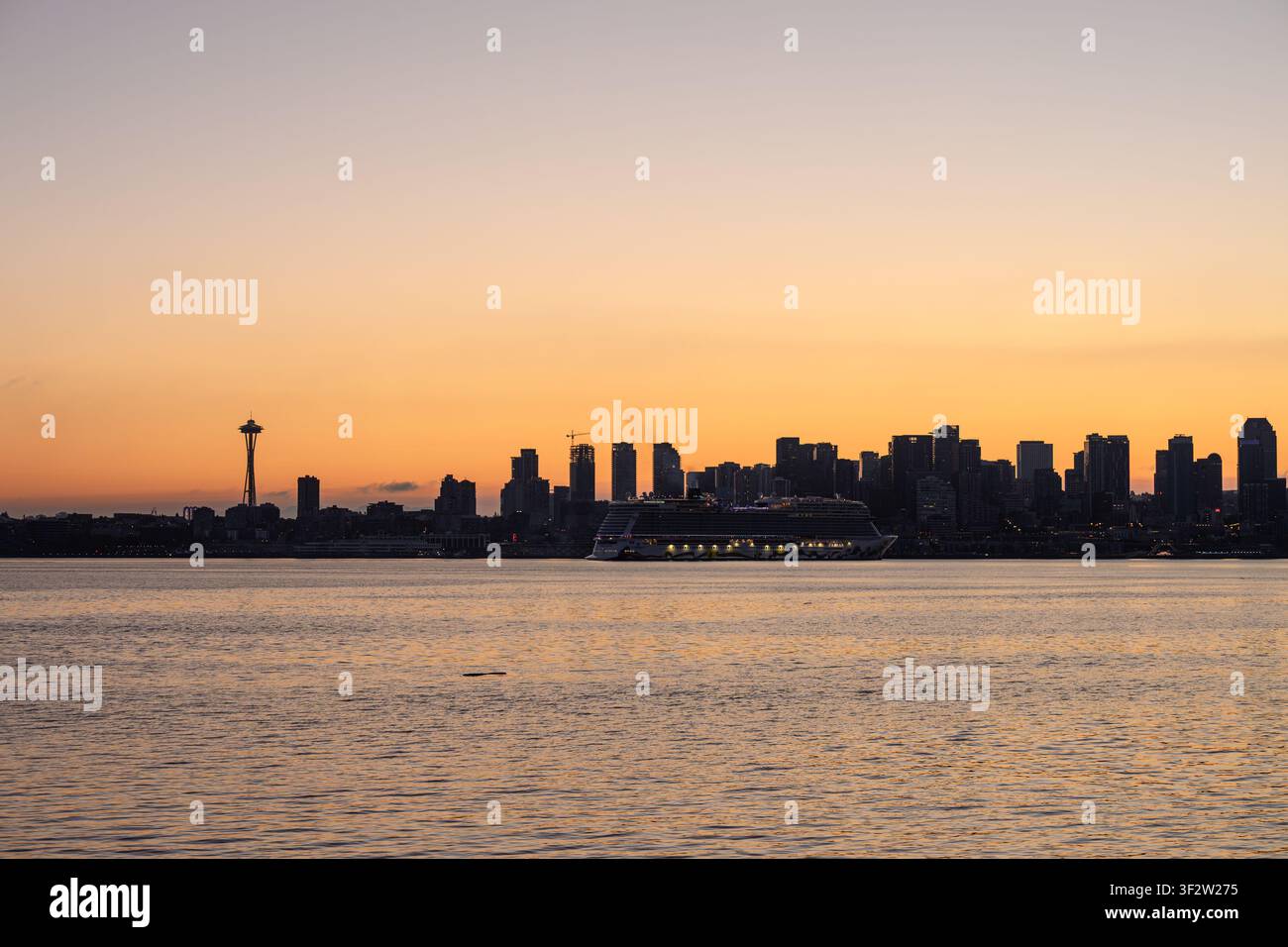 Blick auf die Skyline von Seattle bei Sonnenuntergang mit dem Space Needle und einem großen Kreuzfahrtschiff auf dem Wasser, aufgenommen vom Ufer in Seattle, Washington Stockfoto