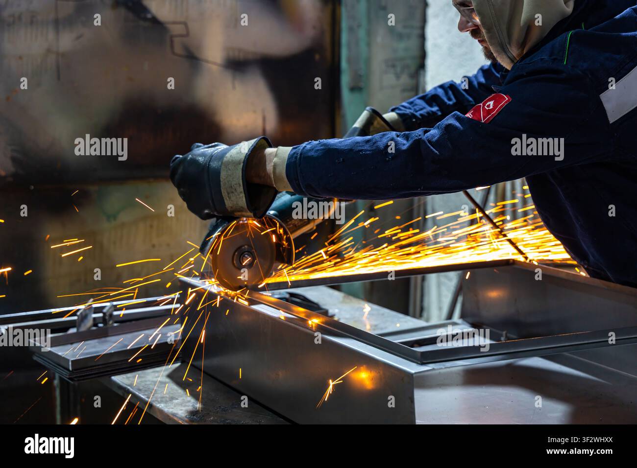 Industriearbeiter schneidet Metall mit einem Winkelschleifer in einer Fertigungswerkstatt Stockfoto