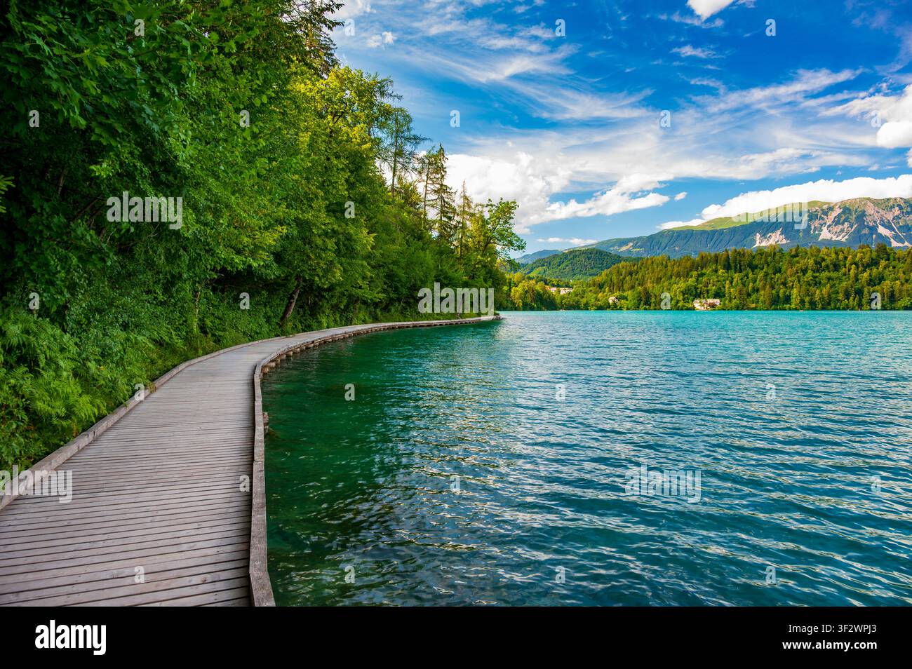 Holzsteg entlang des Ufers des Bleisees in Slowenien, der einen malerischen Wanderweg mit Blick auf den See, die umliegenden Wälder und die Julischen Alpen bietet Stockfoto
