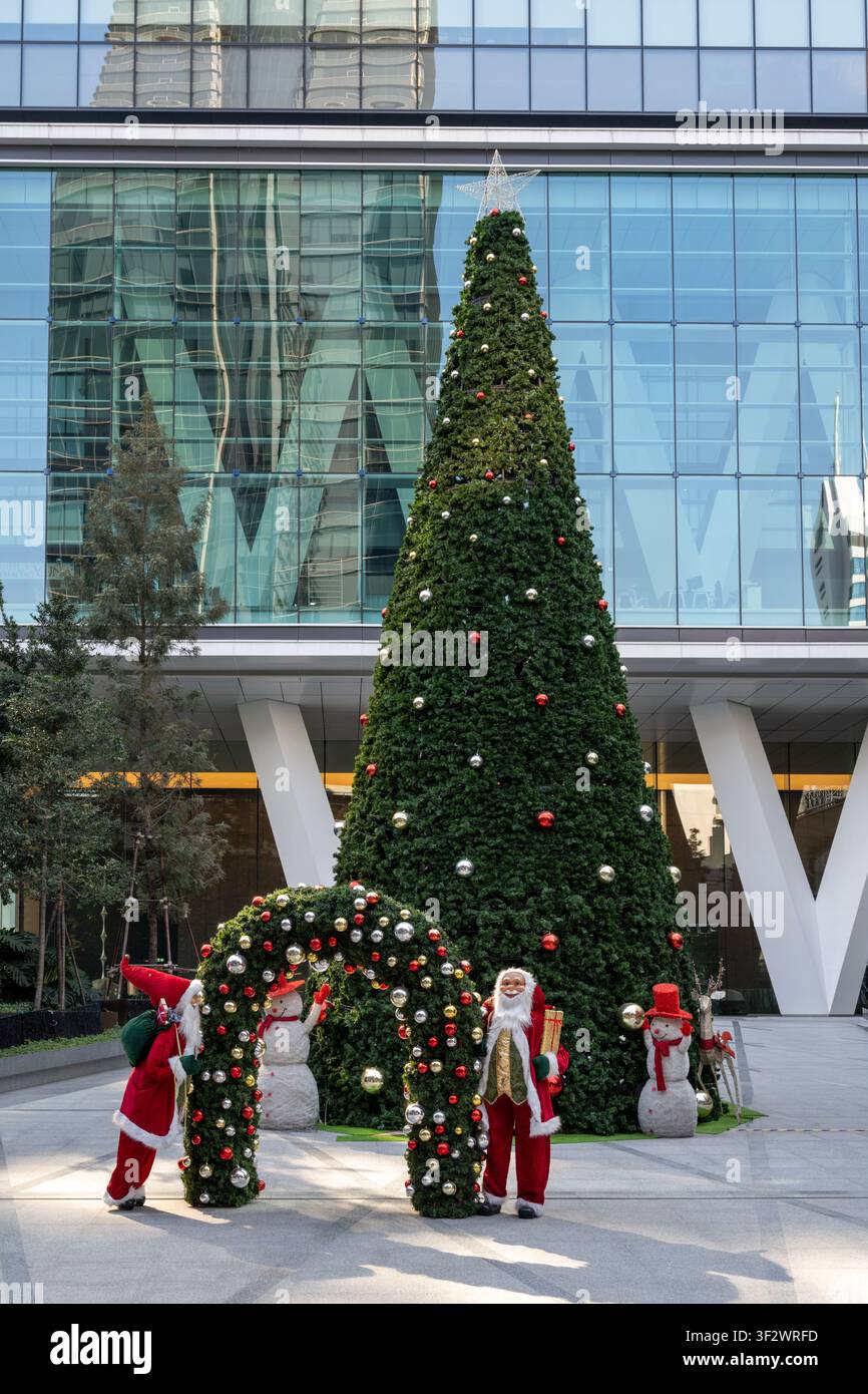 Bangkok Thailandien 11. Januar 2026. Kostümierte Feiertagsdarsteller posieren neben einem geschmückten Weihnachtsbaum, Schneemannfiguren und einem Ornamentbogen vor einem gl Stockfoto