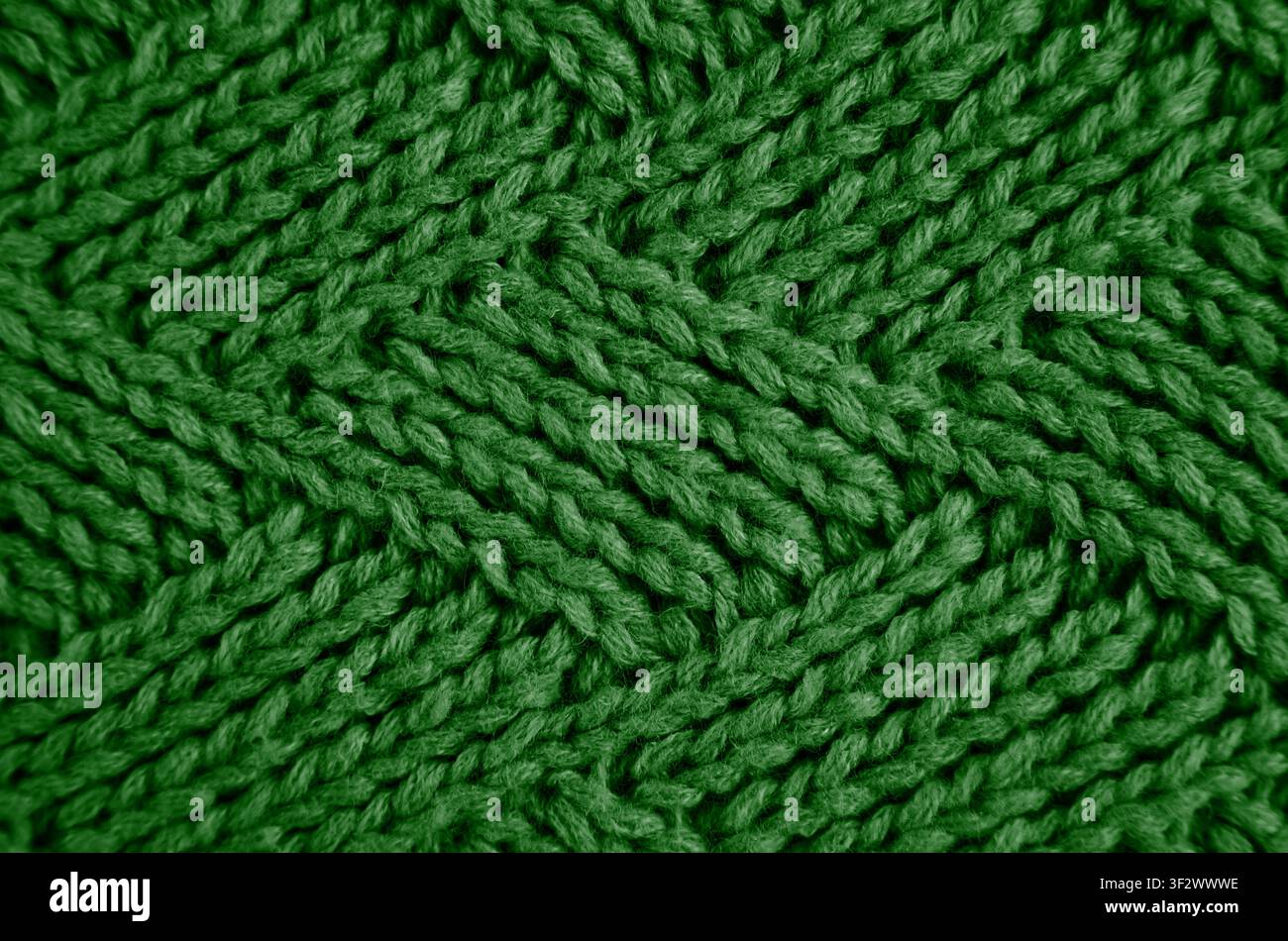 Gestrickter grüner Wollschal mit einem Rautenmuster. Abstrakter Hintergrund. Nahaufnahme. Selektive Schärfentiefe. Stockfoto