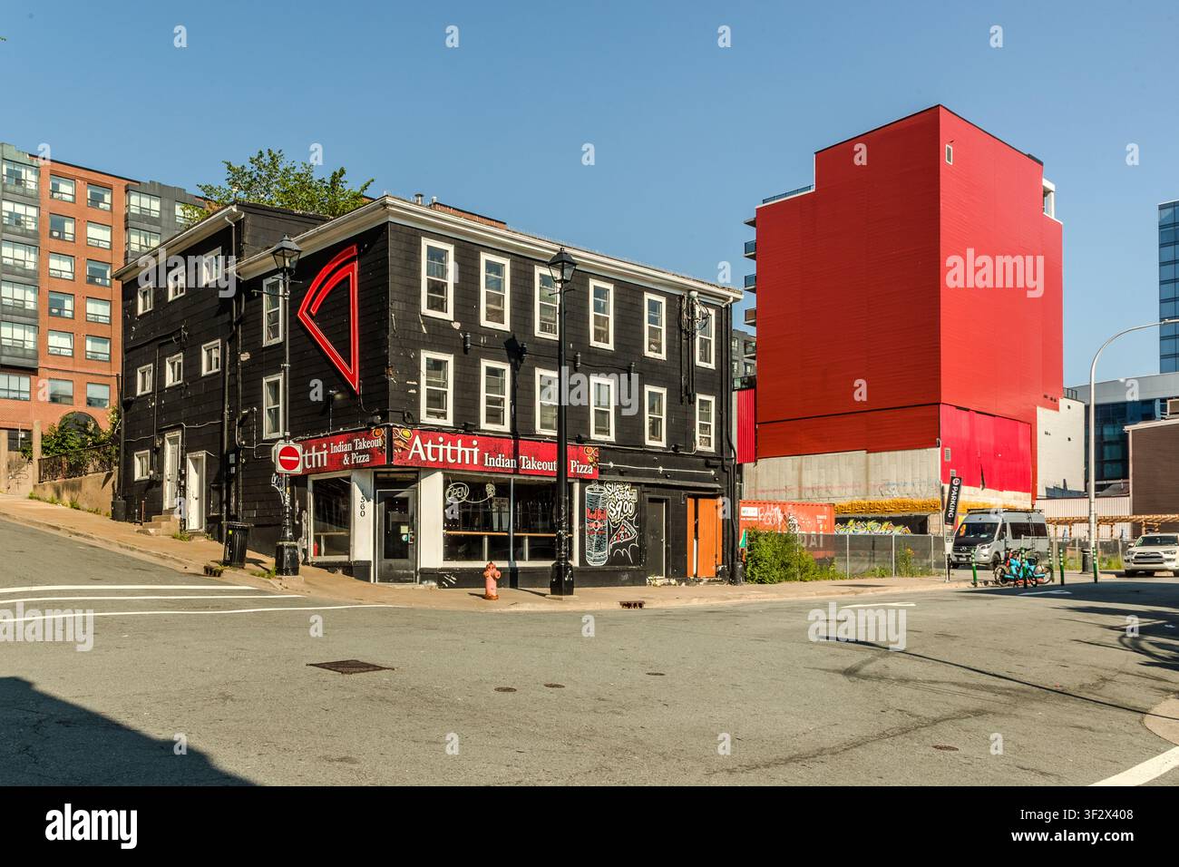 Das indische Imbissrestaurant Atithi Indian Takeout & Pizza, gelegen in einem historischen Holzgebäude in der Barrington Street in Halifax, Kanada. Dahinter steht die leuchtend rote Fassade eines Neubaus. Halifax, Nova Scotia, Kanada Stockfoto