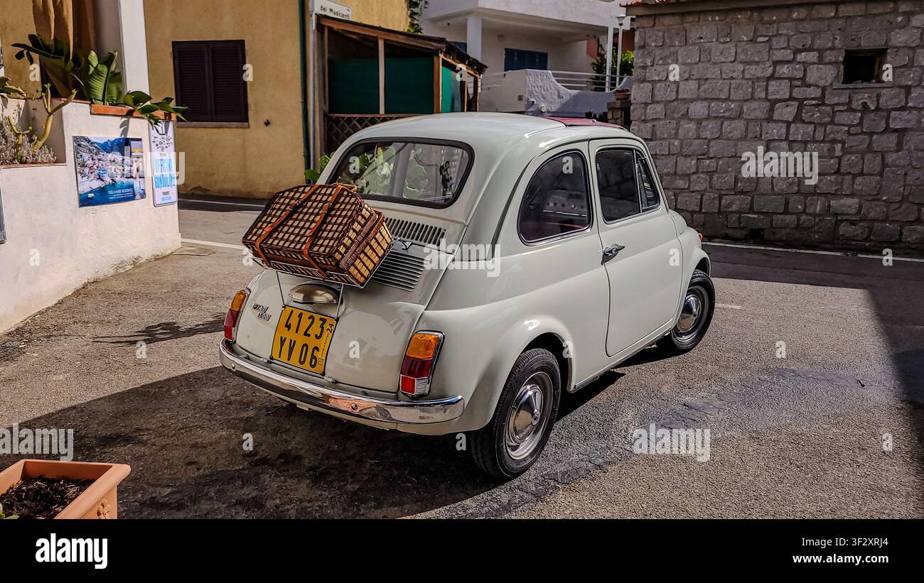 Pomonte, Toskana, Italien – 22. September 2024. Vintage weißer Fiat 500 mit einem Weiden-Picknickkorb auf dem Gepäckträger. Stockfoto