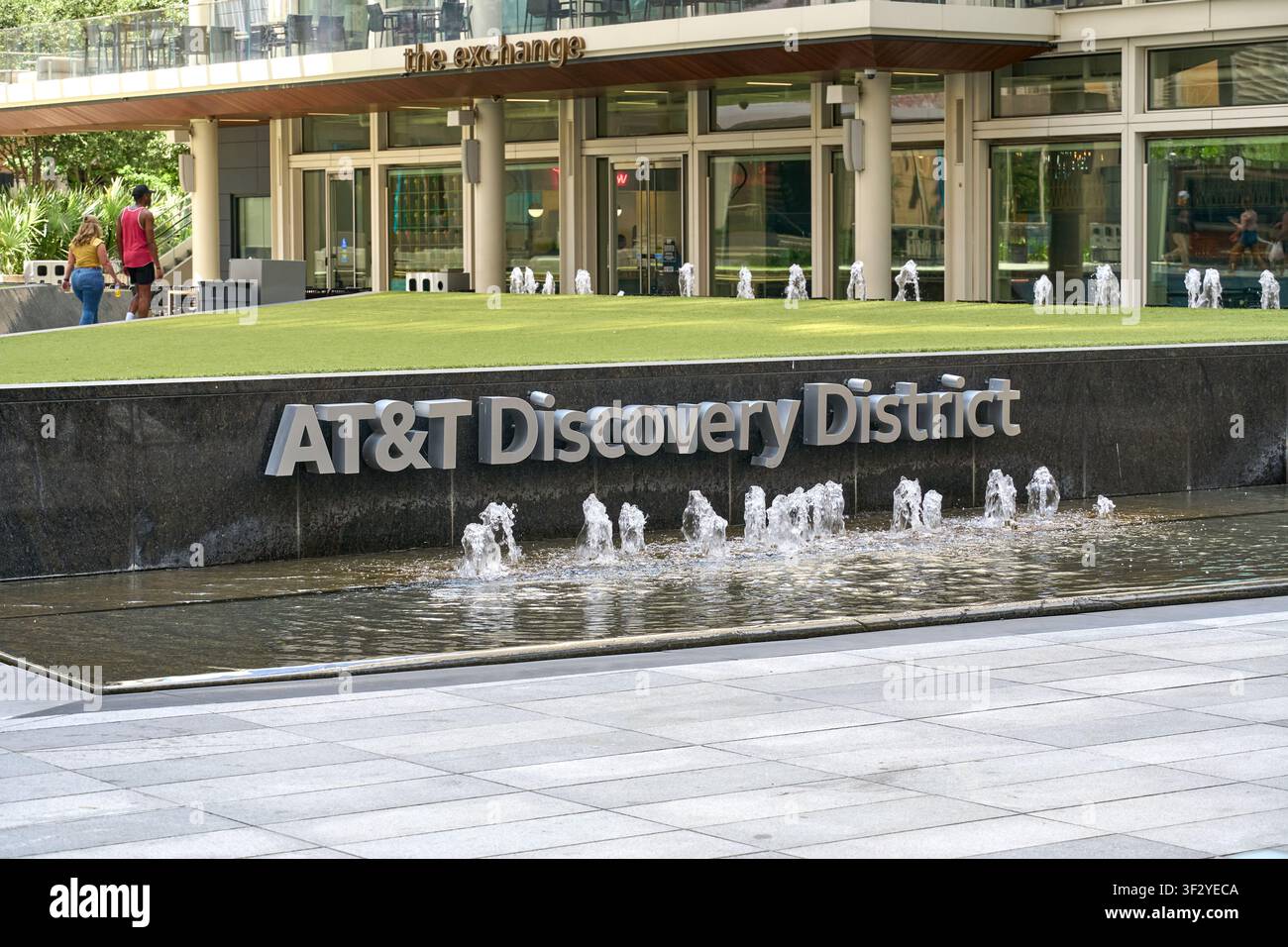 DALLAS, TX, USA - 11. JULI 2026: Blick auf den Brunnenbereich des ATandT Discovery District in Dallas mit Menschen, die in der Nähe spazieren. Das Viertel ist ein beliebt Stockfoto