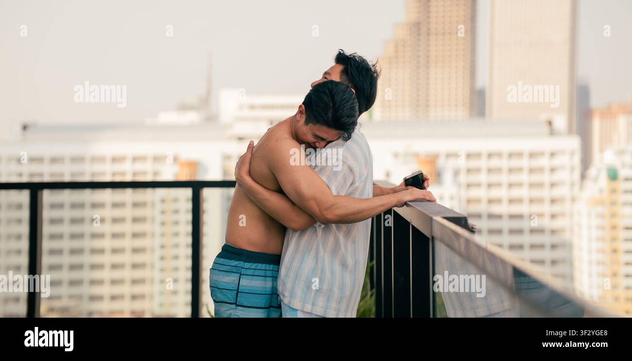 Schwules Paar, das sich auf einem Stadtdach umarmt, Momente der Berührung und Liebe teilt Stockfoto