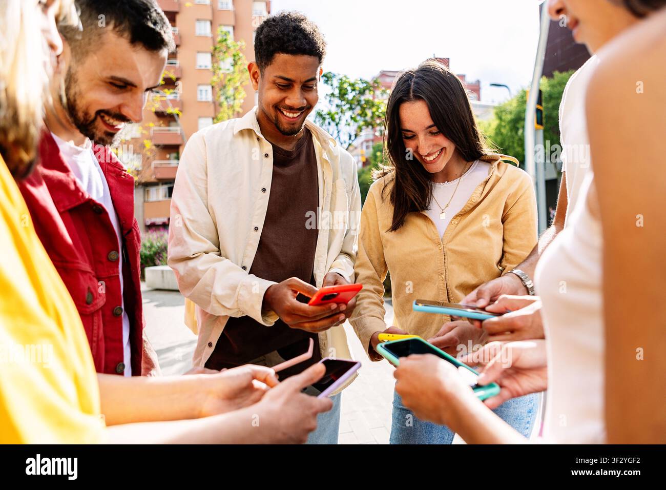 Junge Gruppe von Menschen, die zusammen im Freien Mobiltelefone benutzen Stockfoto