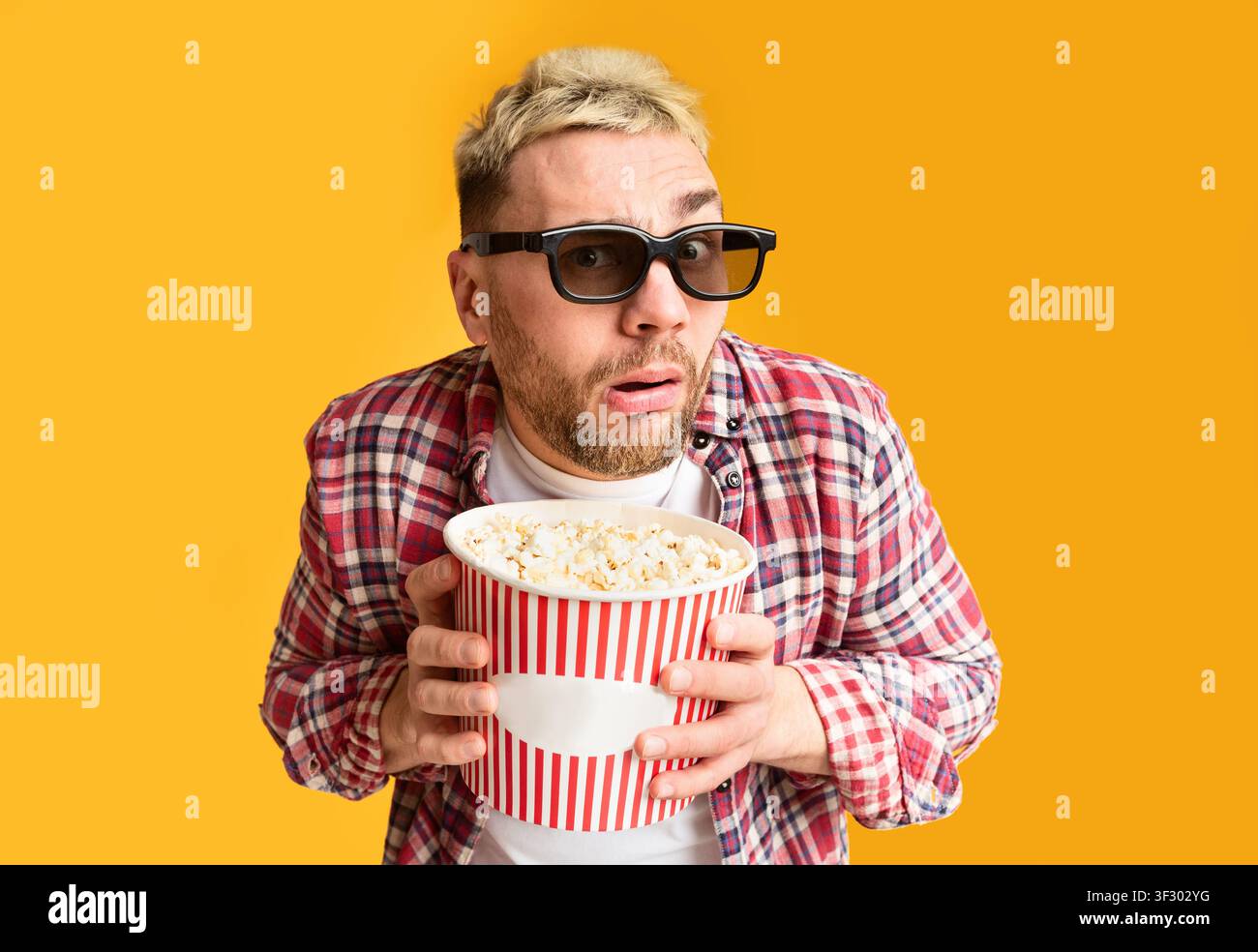 Filmabend. Überraschter Kerl, der lustig am Eimer hält Stockfoto