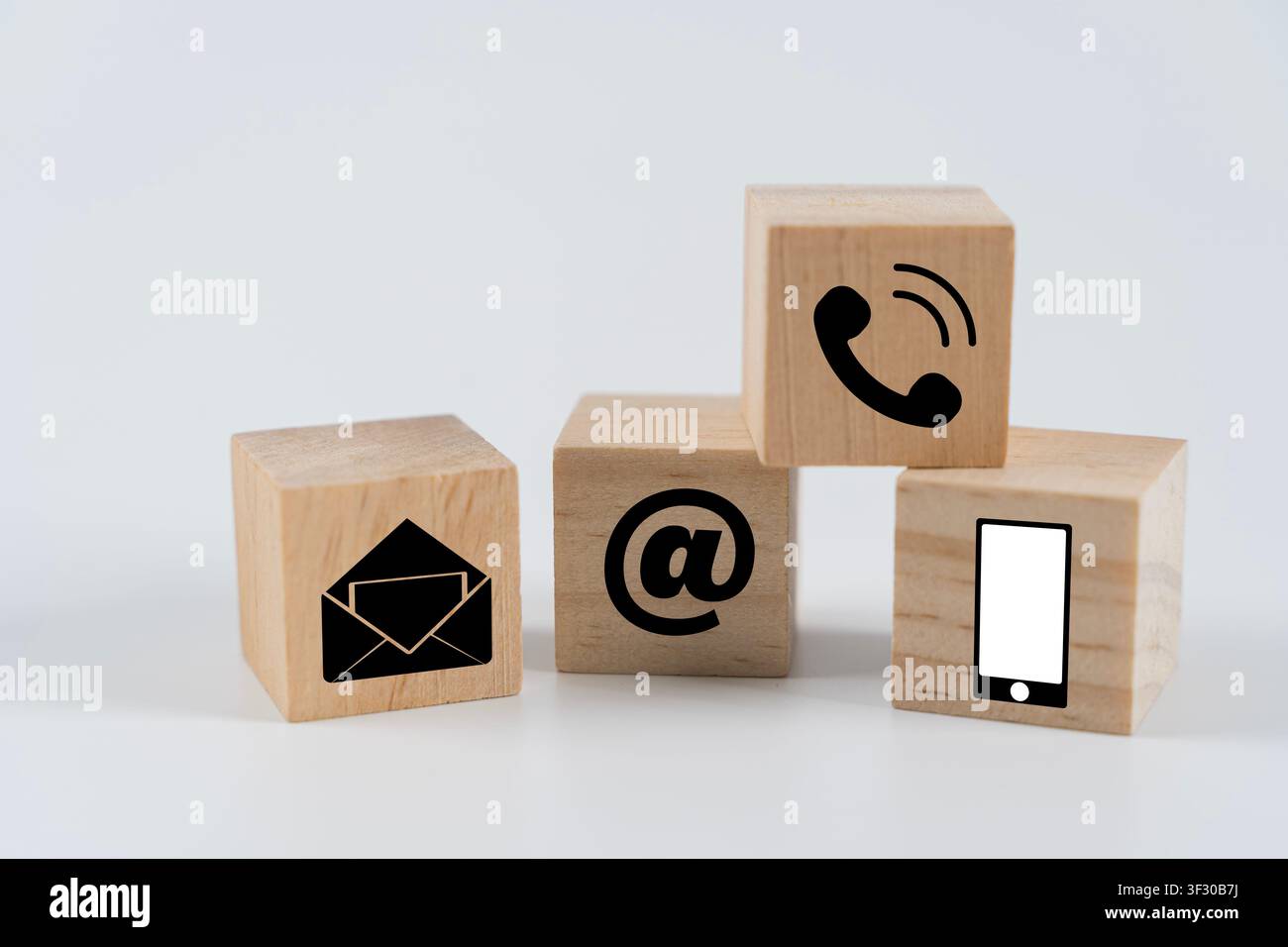 Hölzerne Würfel, die mit Telefon-, E-Mail-, At-Zeichen- und Smartphone-Symbolen angeordnet sind, repräsentieren Mehrkanal-Kontakt, digitale Kommunikation, Kundensupport, Online Stockfoto
