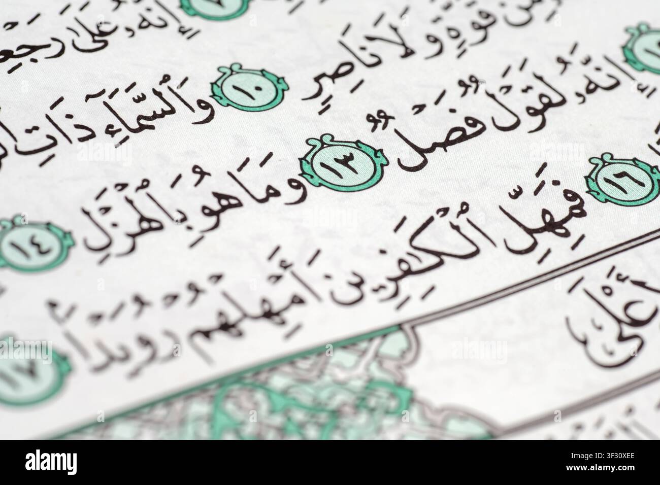Detaillierte Makroaufnahme des Heiligen Korans mit arabischer Kalligraphie und Versmarkierungen. Das Bild fängt den heiligen Text der Sure At-Tariq mit elegan Stockfoto