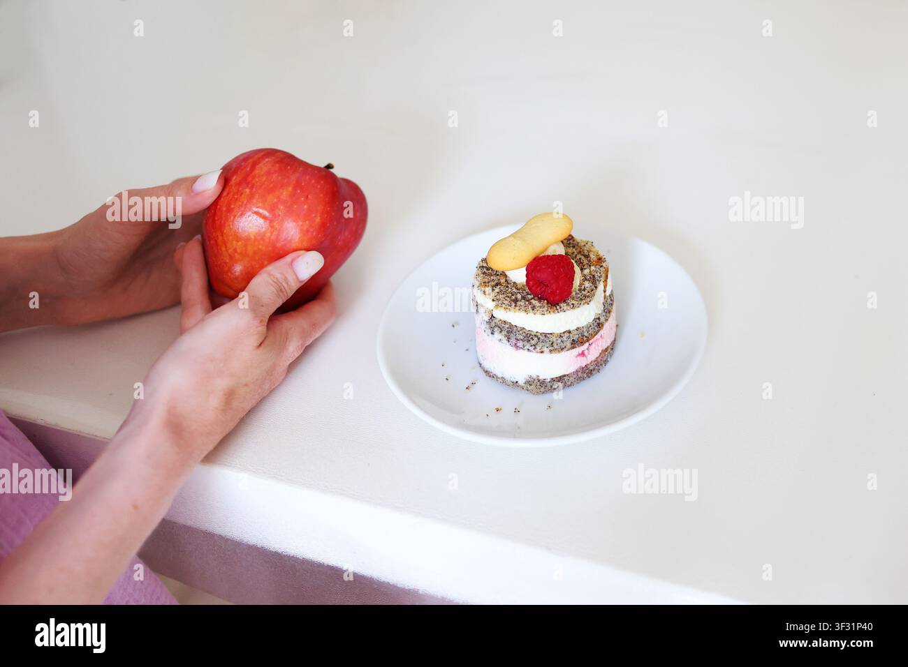 Hände, die zwischen einem frischen Apfel und einem geschichteten Dessert wählen, um gesundes Essen, achtsame Ernährung und ausgewogene Lebensmittelauswahl zu veranschaulichen. Stockfoto