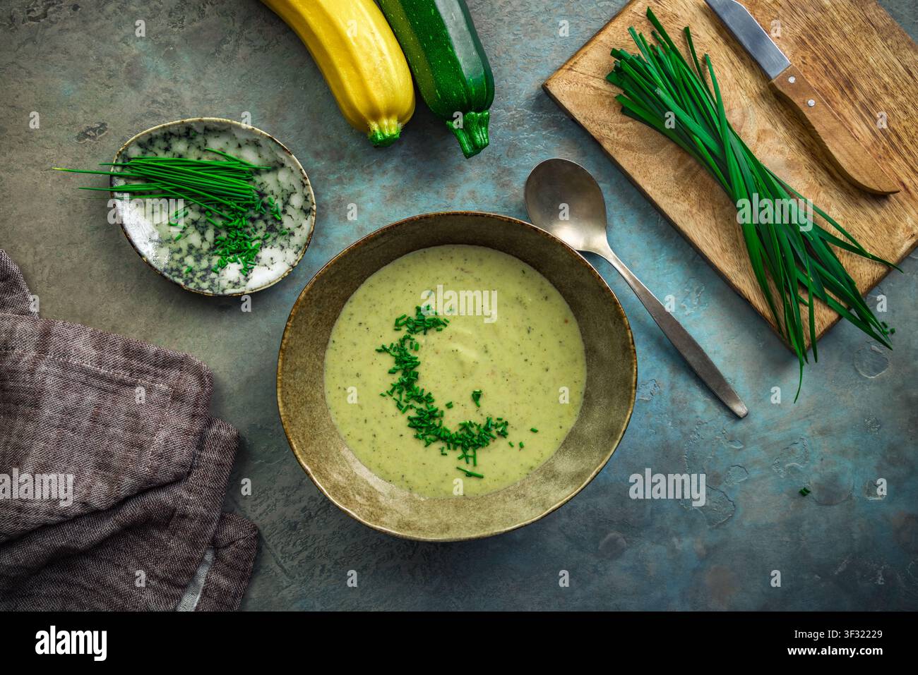 Kremige Zucchinisuppe, garniert mit frischem Schnittlauch, serviert in einer rustikalen Schüssel Stockfoto