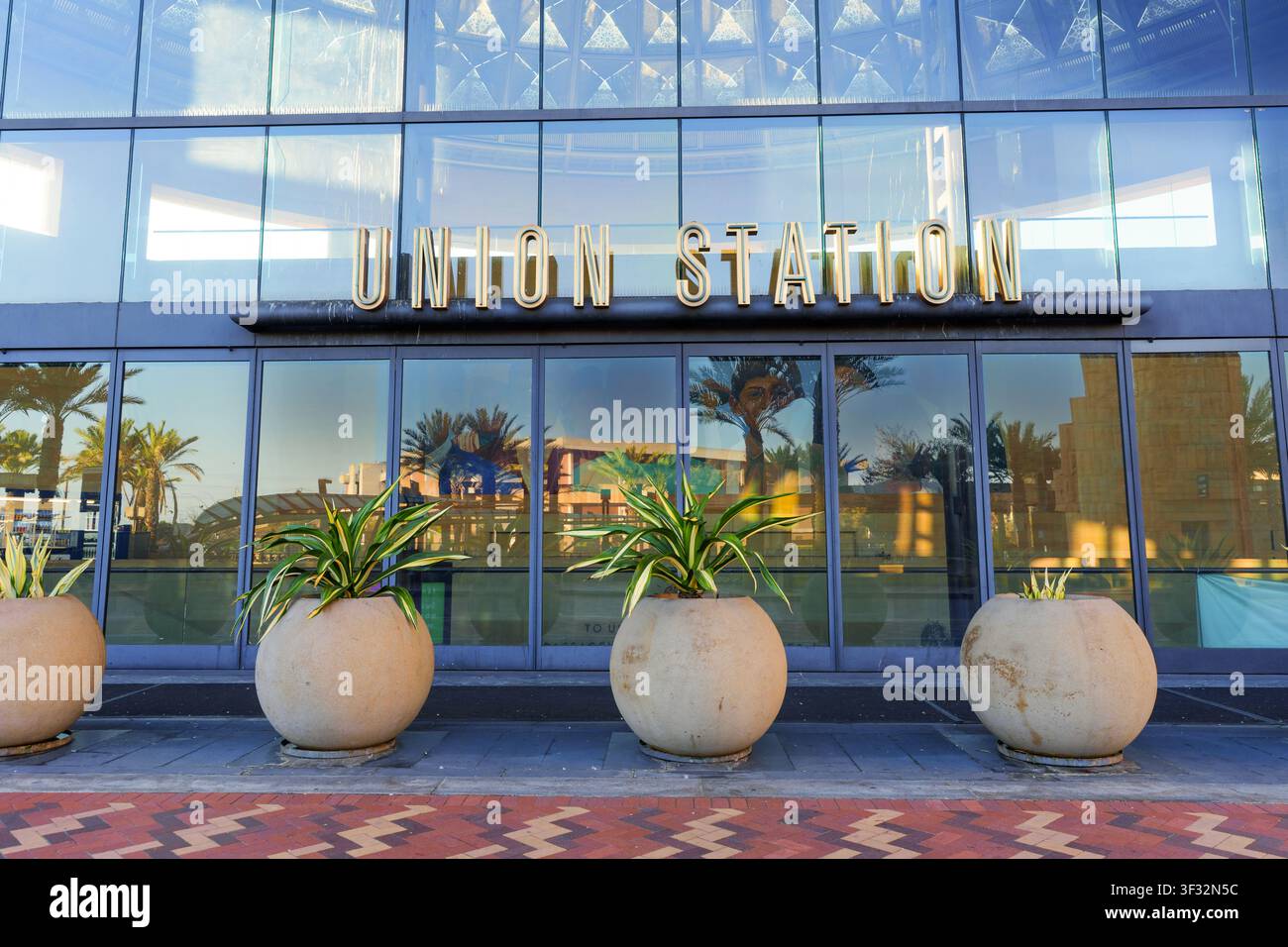 Los Angeles, Kalifornien - 25. Januar 2026: Das goldene Schild der Union Station thront über einem modernen Glaseingang, der Palmen widerspiegelt, mit einem großen runden Platz Stockfoto