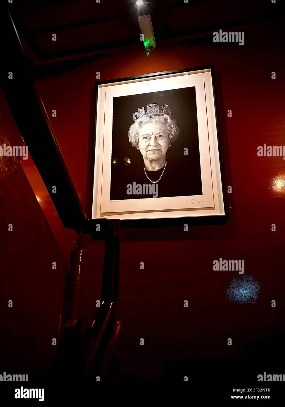 Rahmengemälde von Königin Elizabeth II an einer Treppenhauswand in einem traditionellen Londoner Pub, England, UK - Smartphone-aufgenommenes Stockfoto