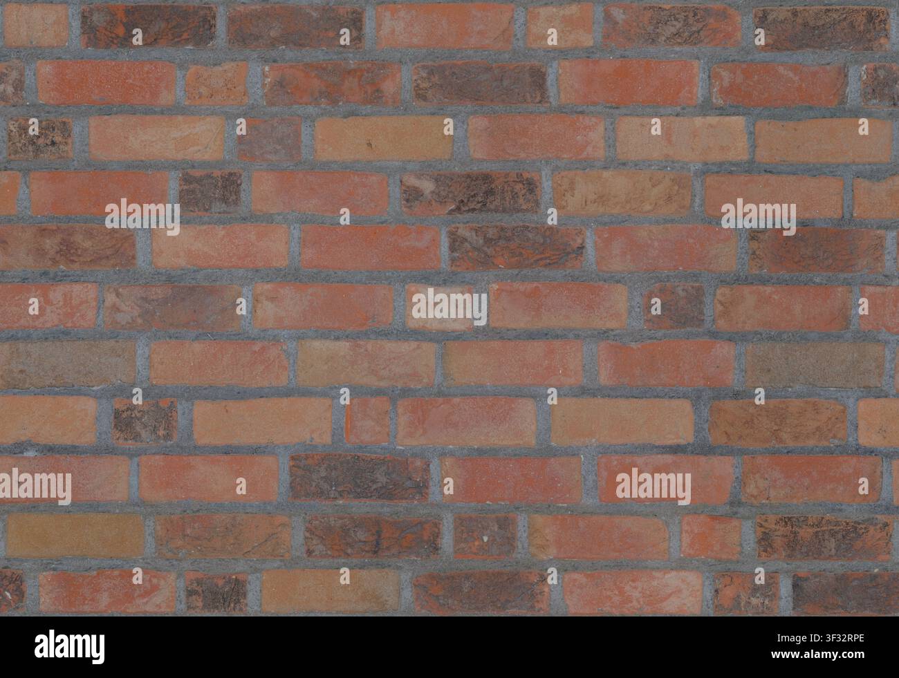 Eine flache rustikale rote, orange und braune Ziegelwandtextur mit grauen Mörtelfugen. Stockfoto