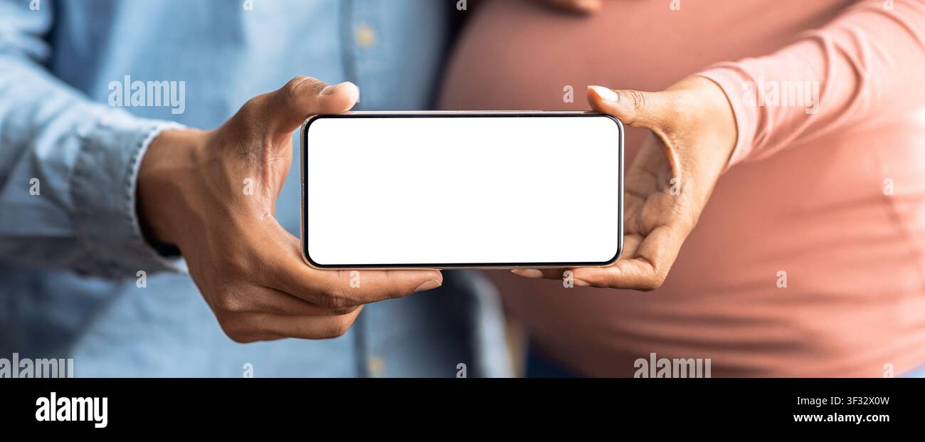 Paar hält Smartphone mit leerem Bildschirm, erwartet ein Baby, Schwangerschaftskonzept Stockfoto