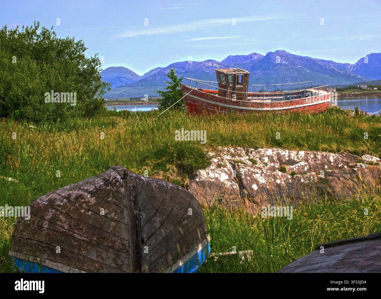 Ein altes Fischerboot, das an Land gezogen, vernachlässigt und zurückgelassen am Ende seines Arbeitslebens liegt. In Roundstone, Connemara, County Galway, Irland Stockfoto